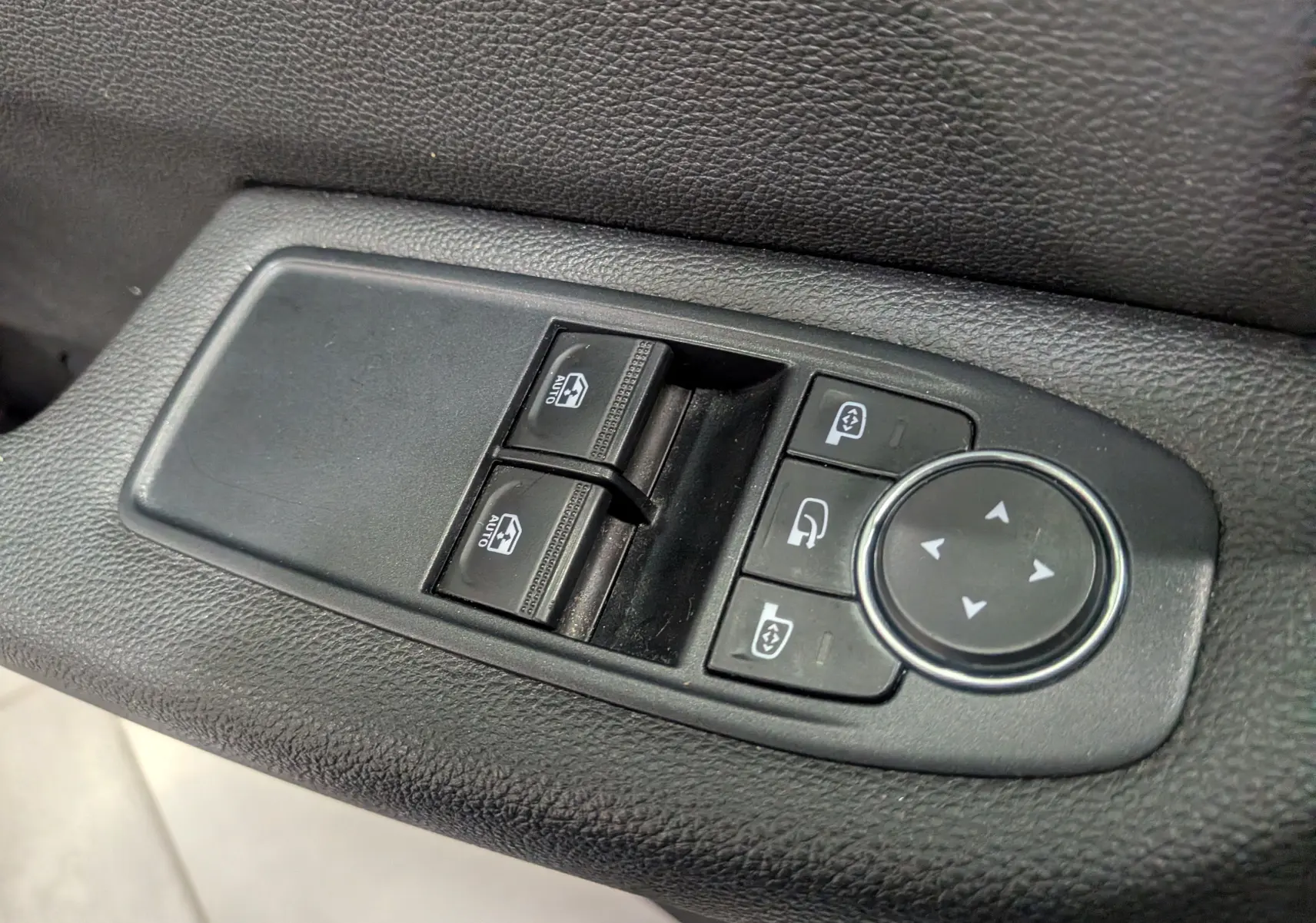 Gros plan sur les commandes de lève-vitres et réglage des rétroviseurs côté conducteur d'une Renault Clio V Business 2020.