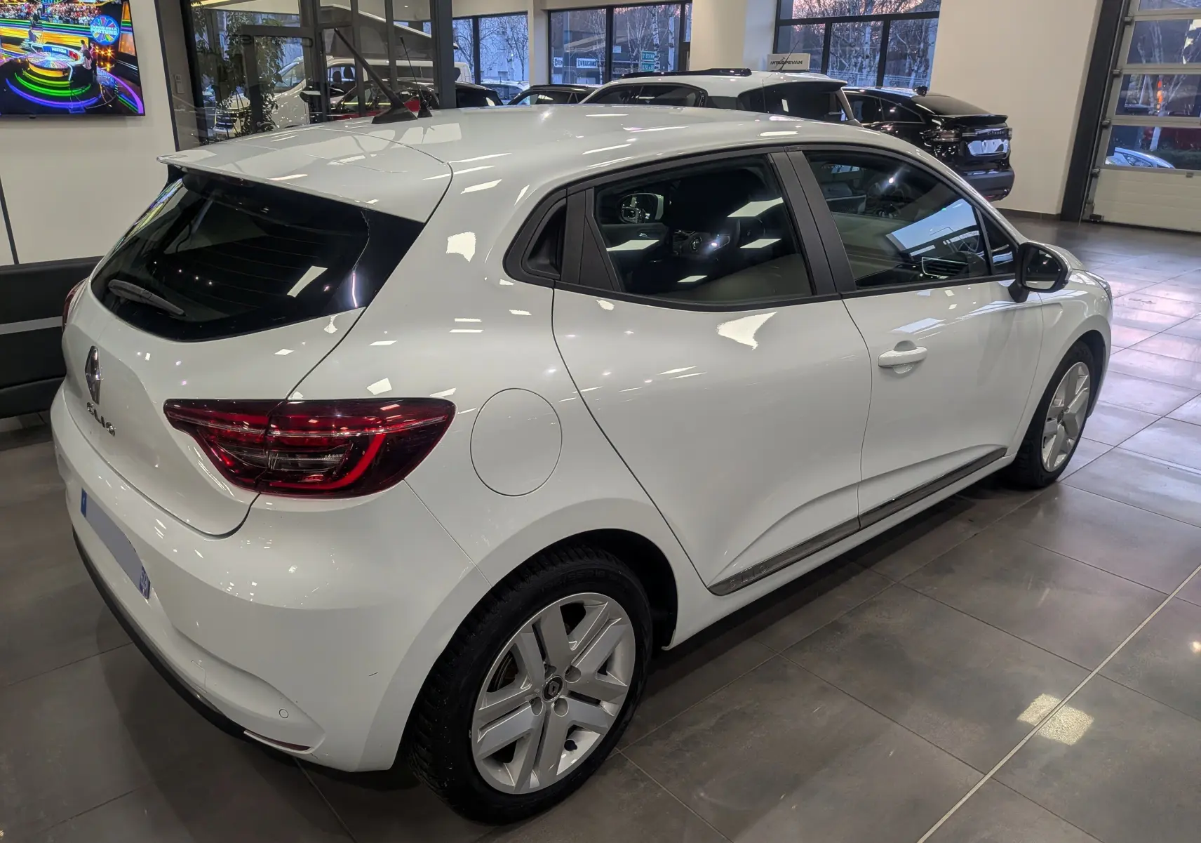 Renault Clio V Blue dCi 115 Business blanc glacier vue 3/4 arrière droit en intérieur showroom.