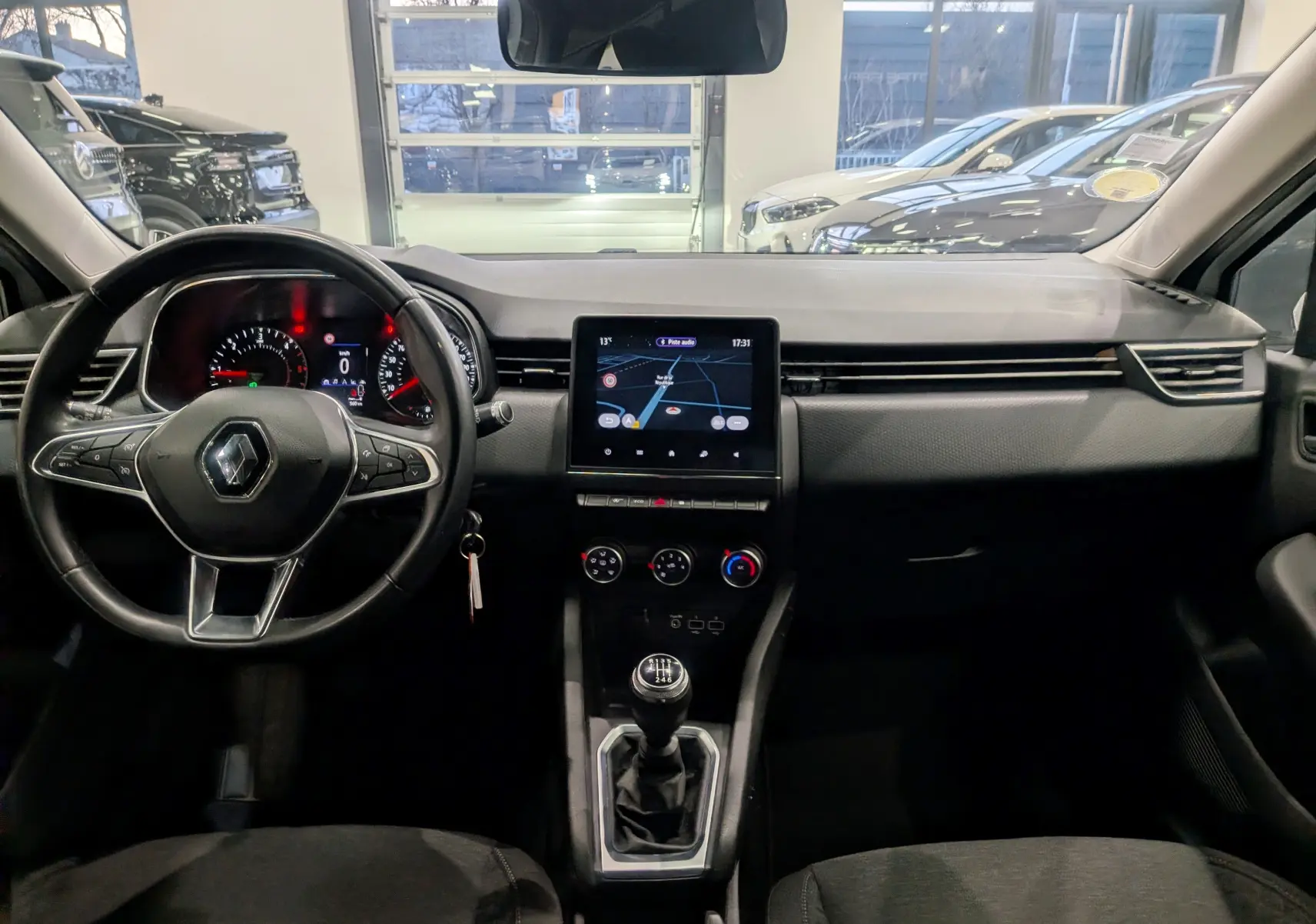 Vue intérieure avant de la Renault Clio V Business 2020, tableau de bord noir avec écran tactile et levier de vitesse manuel.