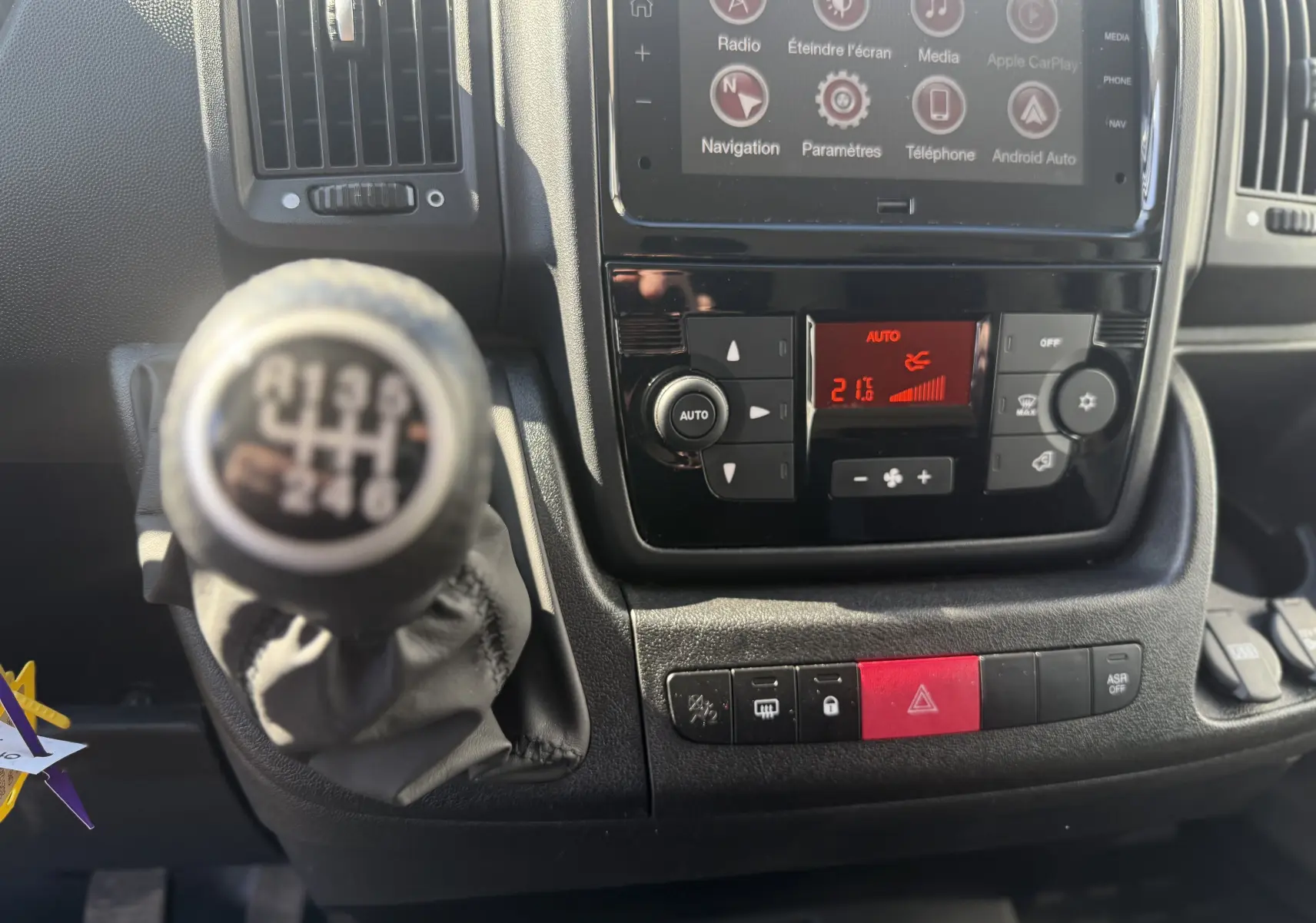Gros plan sur la console centrale et levier de vitesses manuel de l’Opel Movano Fourgon blanc, avec écran tactile et commandes climatisation.