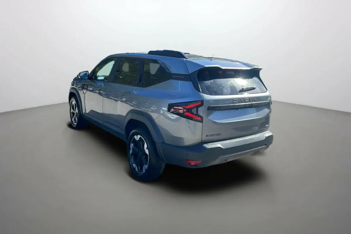 Vue 3/4 arrière droite du Dacia Bigster gris schiste avec jantes alu noires et toit ouvrant panoramique visible.