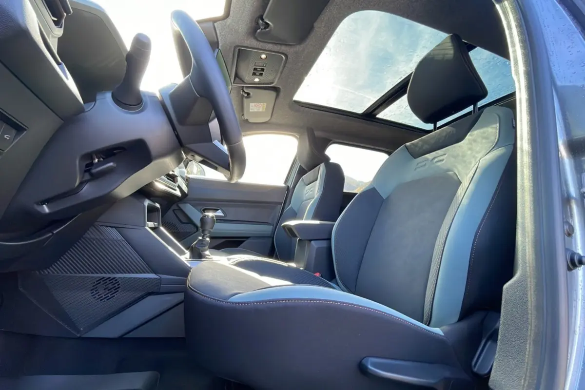 Vue intérieure côté conducteur du Dacia Bigster 2025 avec sièges cuir bi-ton, toit ouvrant panoramique et volant cuir.