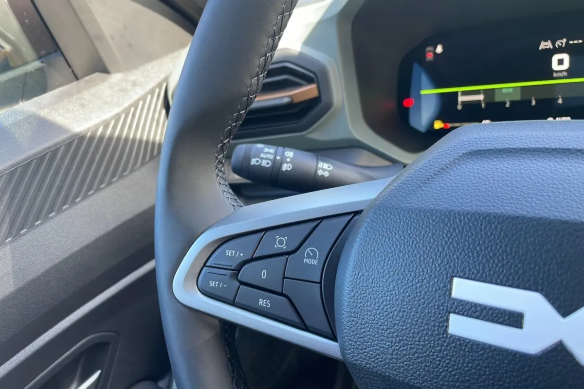 Gros plan sur le volant cuir noir du Dacia Bigster 2025, avec commandes intégrées et tableau de bord digital visible.