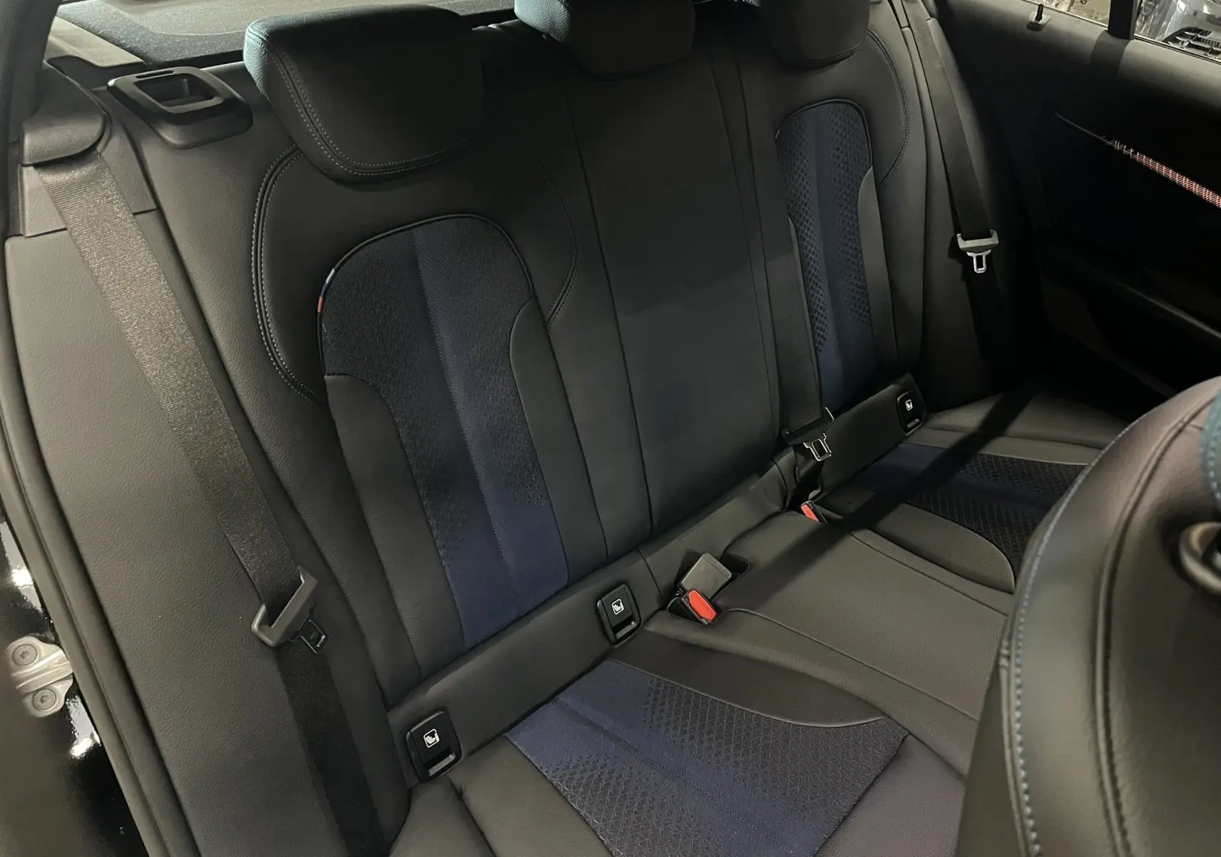 Vue intérieure sur la banquette arrière cuir noir et tissu bleu avec surpiqûres bleues de la BMW Série 1 F40 M Sport 2020.