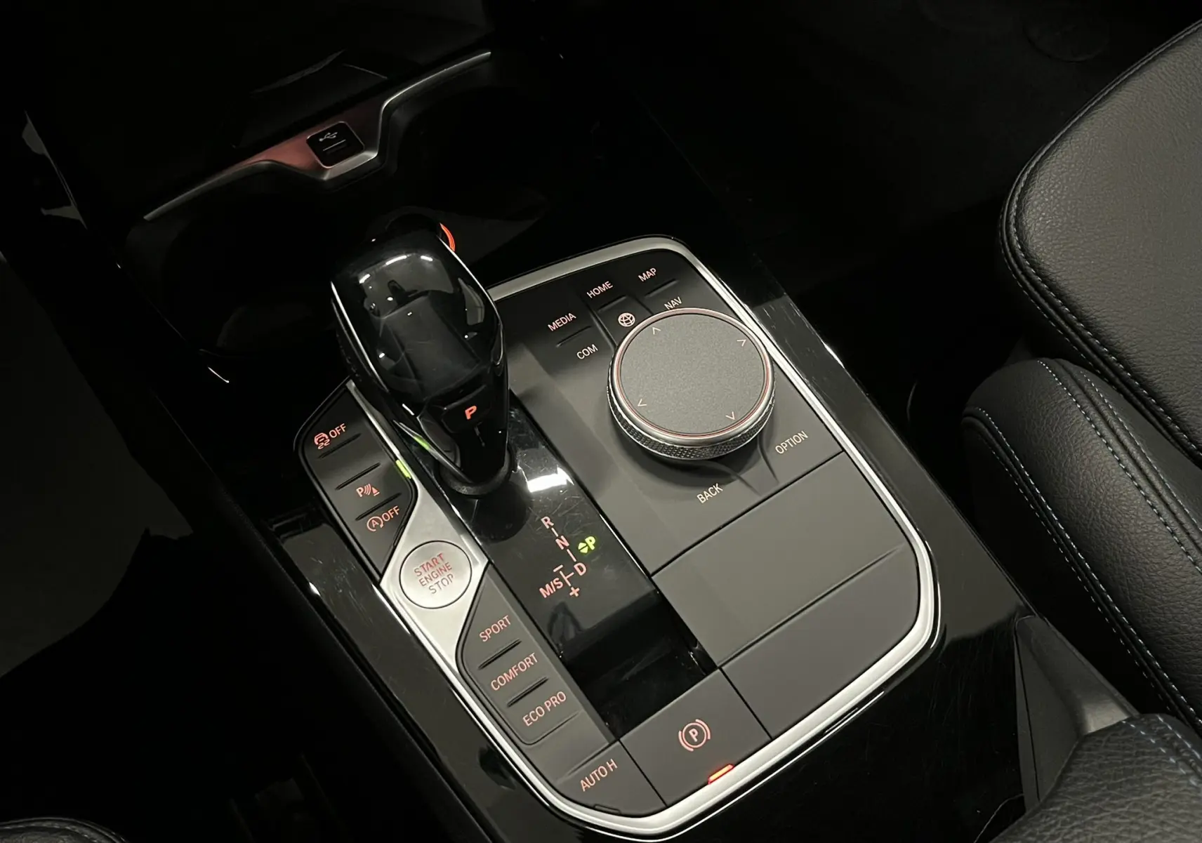Gros plan sur la console centrale noire brillante de la BMW Série 1 F40 118dA avec levier de vitesses et commandes de mode de conduite.