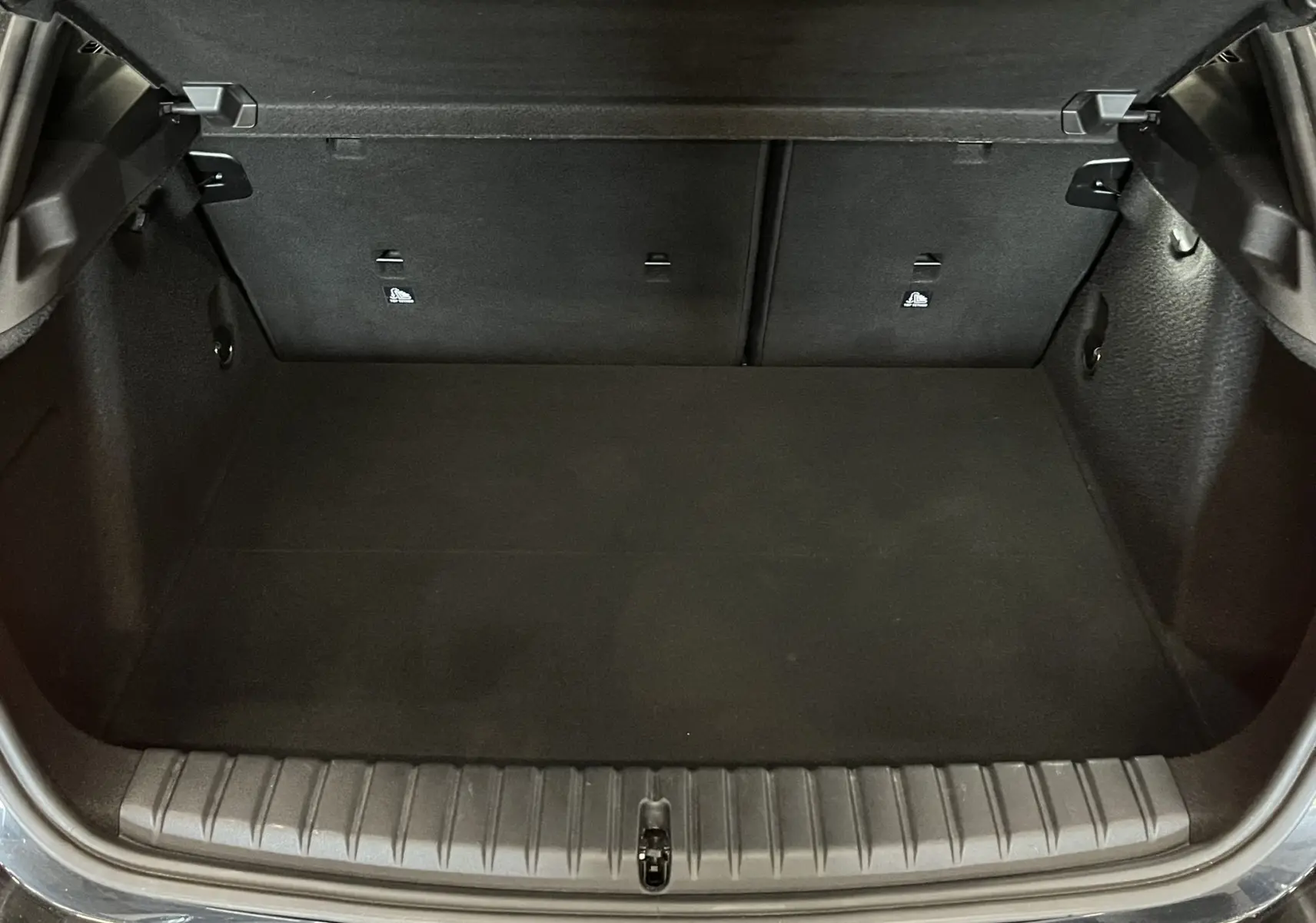 Coffre ouvert vu de face d'une BMW Série 1 F40 118dA noir métallisé, avec banquette arrière rabattable et intérieur noir.