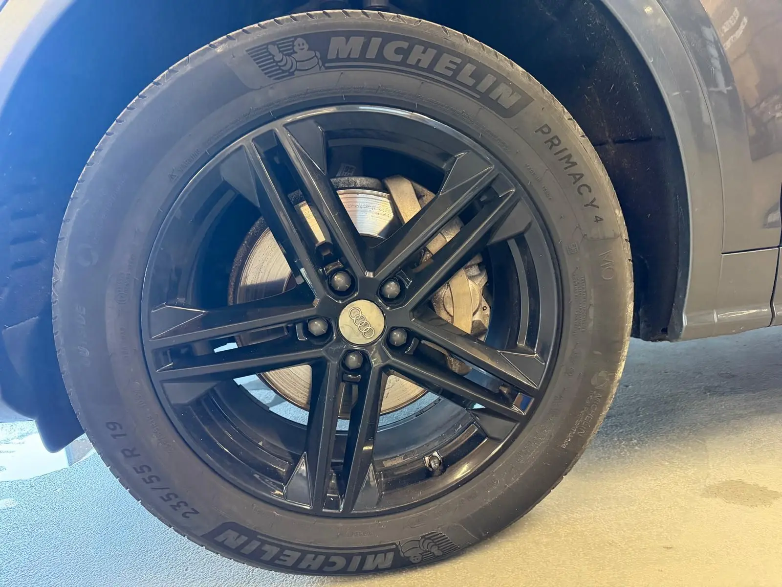 Gros plan sur la roue avant droite noire avec jante Audi en alliage du Q5 Sportback gris 2019.