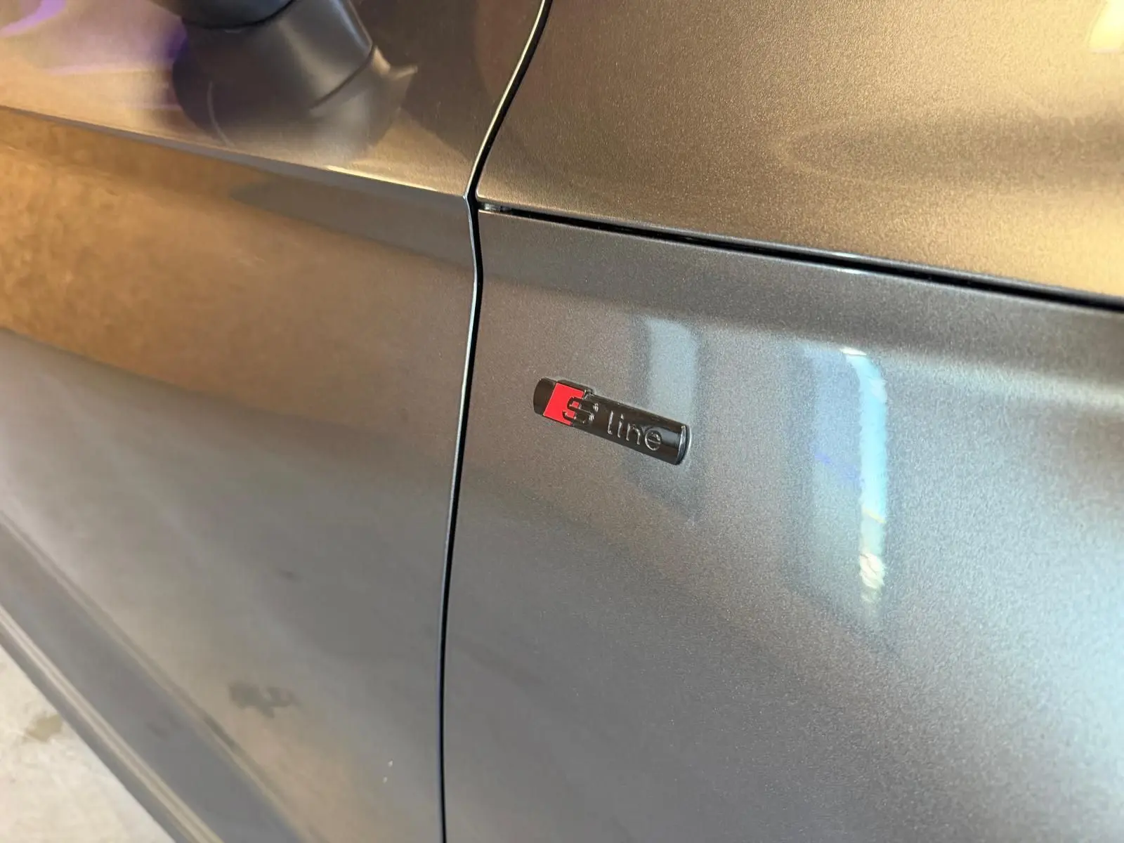 Détail du logo S line sur la portière côté gauche d’un Audi Q5 Sportback gris métallisé.
