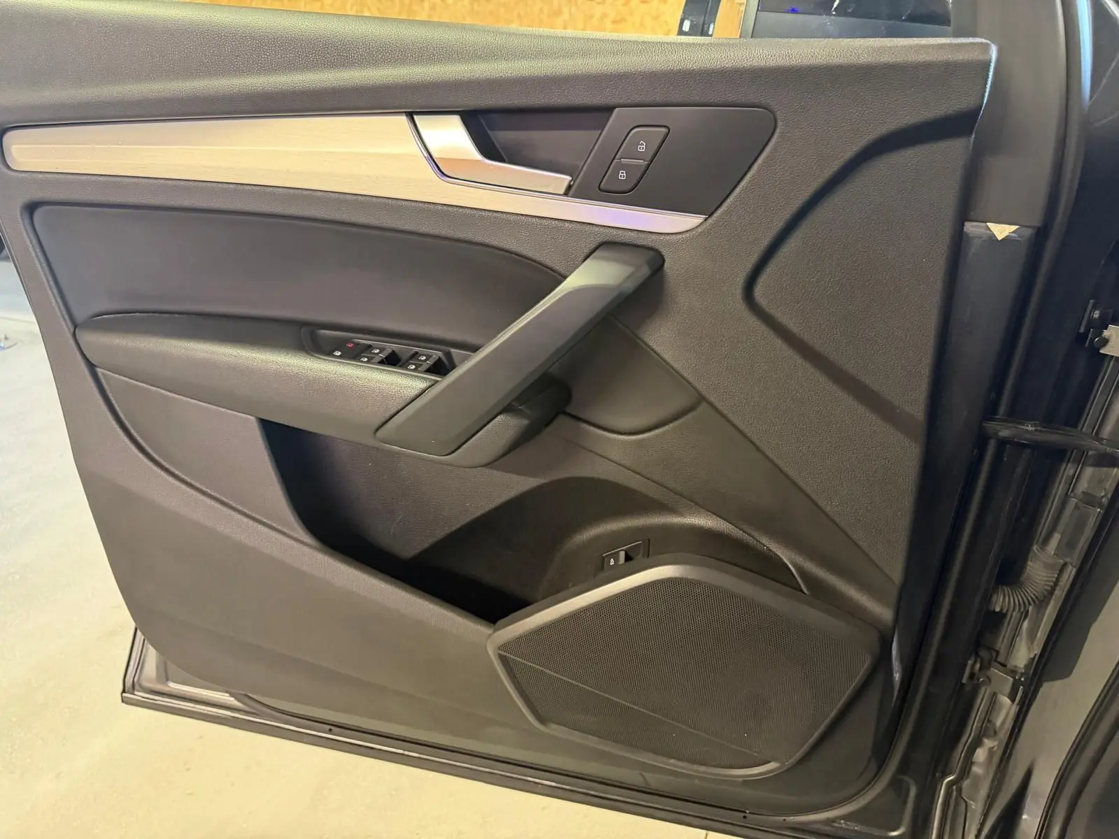 Vue intérieure côté gauche de la porte avant gris foncé de l'Audi Q5 Sportback avec insert bois et commandes de vitres.