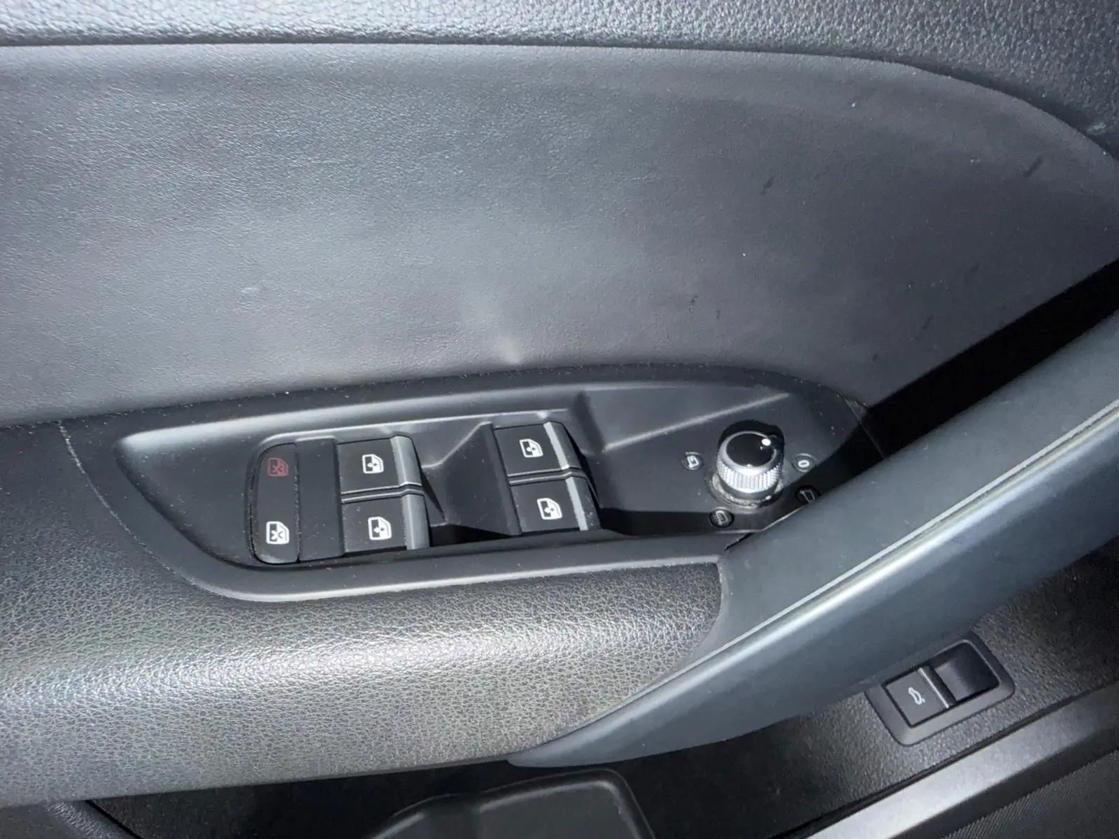 Gros plan sur les commandes de lève-vitres et rétroviseurs côté conducteur d’Audi Q5 Sportback gris, intérieur noir.
