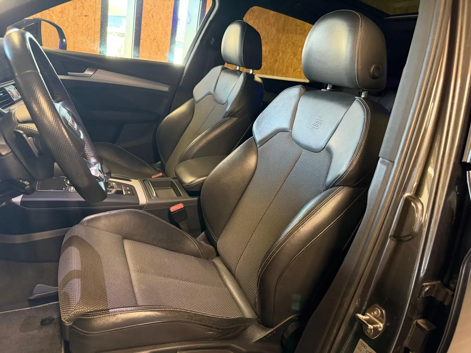 Vue intérieure côté gauche de l'Audi Q5 Sportback 2019 avec sièges avant noirs en cuir et tissu S-Line.