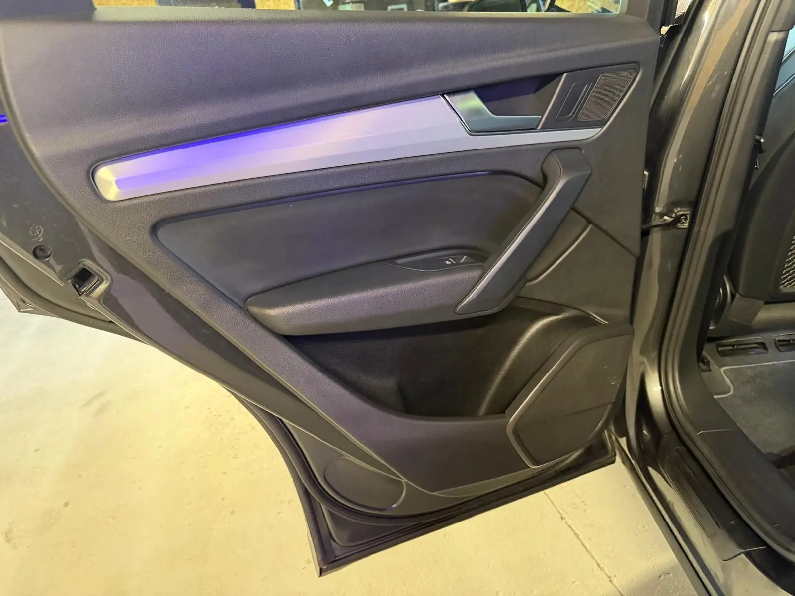 Vue rapprochée de la porte arrière droite gris foncé de l’Audi Q5 Sportback 2019 avec garniture noire et insert aluminium.