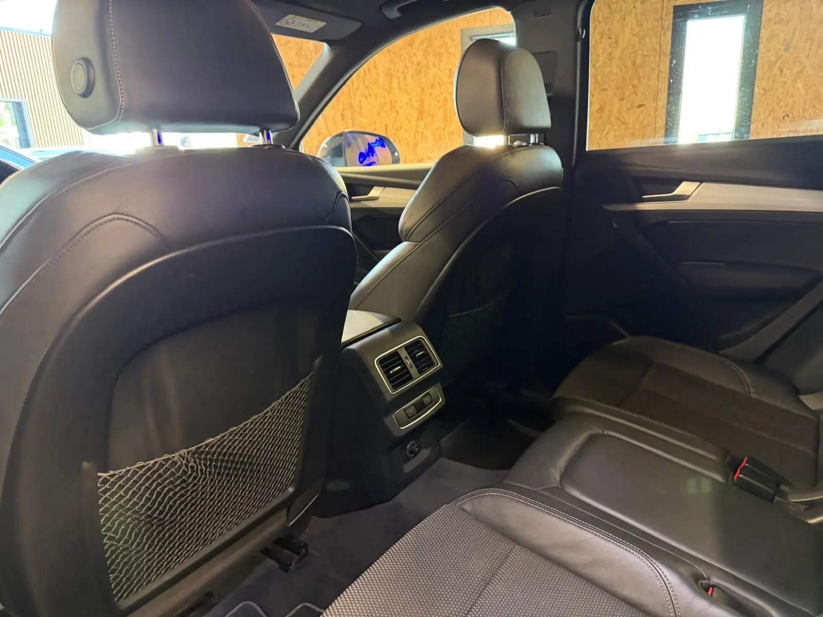 Vue intérieure arrière de l'Audi Q5 Sportback 2019, sièges en cuir noir avec filet de rangement au dos des sièges avant.