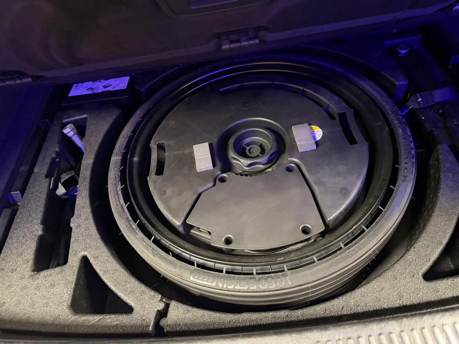 Vue rapprochée de la roue de secours noire dans le coffre d’un Audi Q5 Sportback gris 2019.