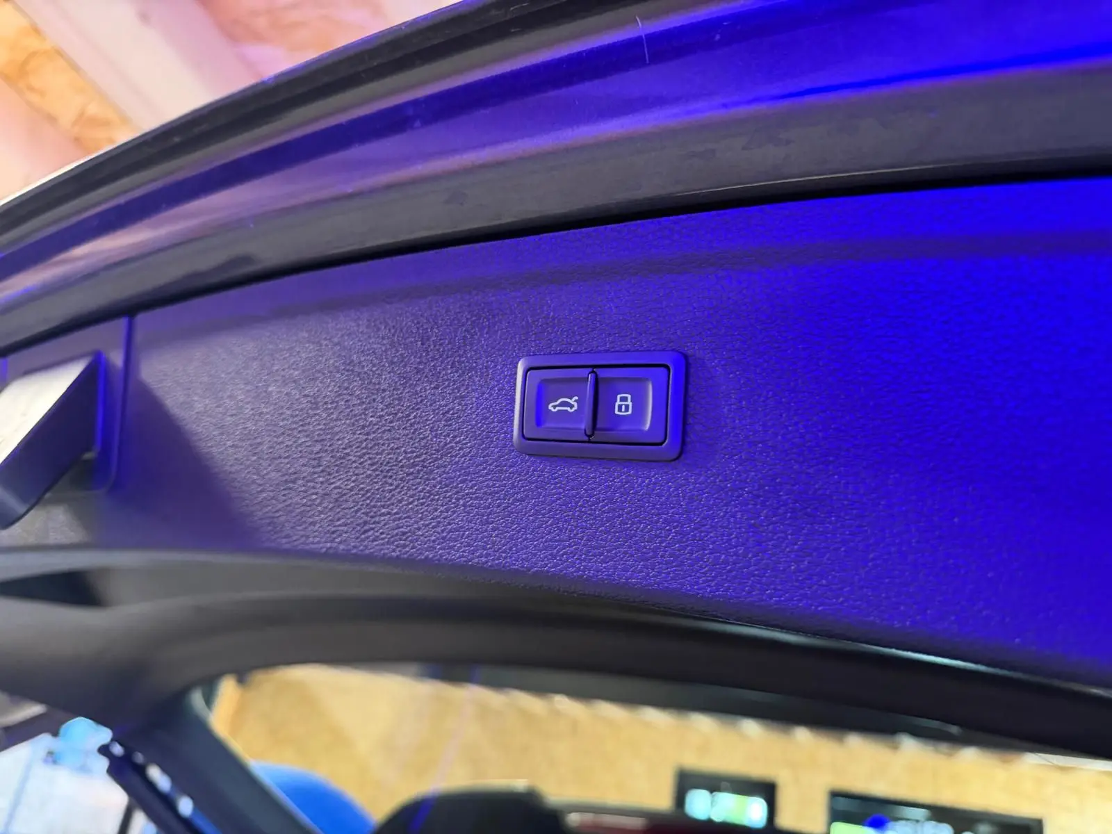 Boutons d'ouverture et de verrouillage électrique du hayon sur la partie intérieure du coffre d'un Audi Q5 gris.