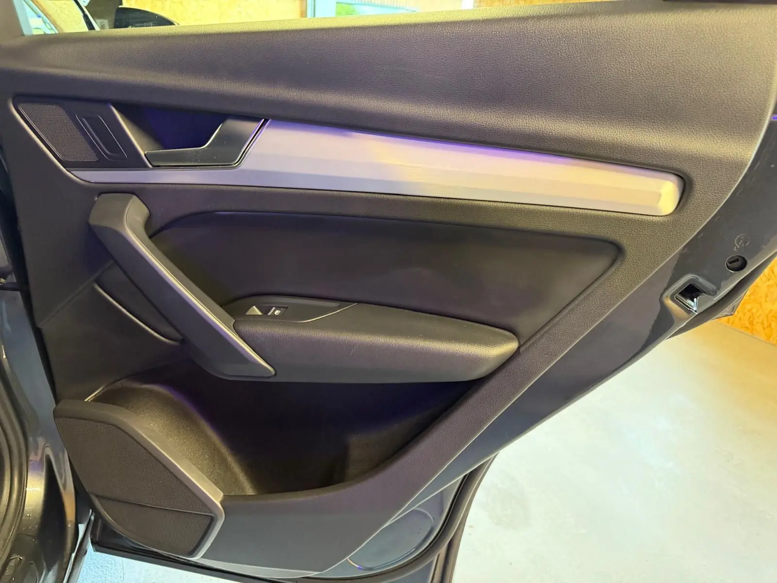 Vue rapprochée de la porte arrière droite de l’Audi Q5 Sportback gris, avec garniture noire et insert argenté.
