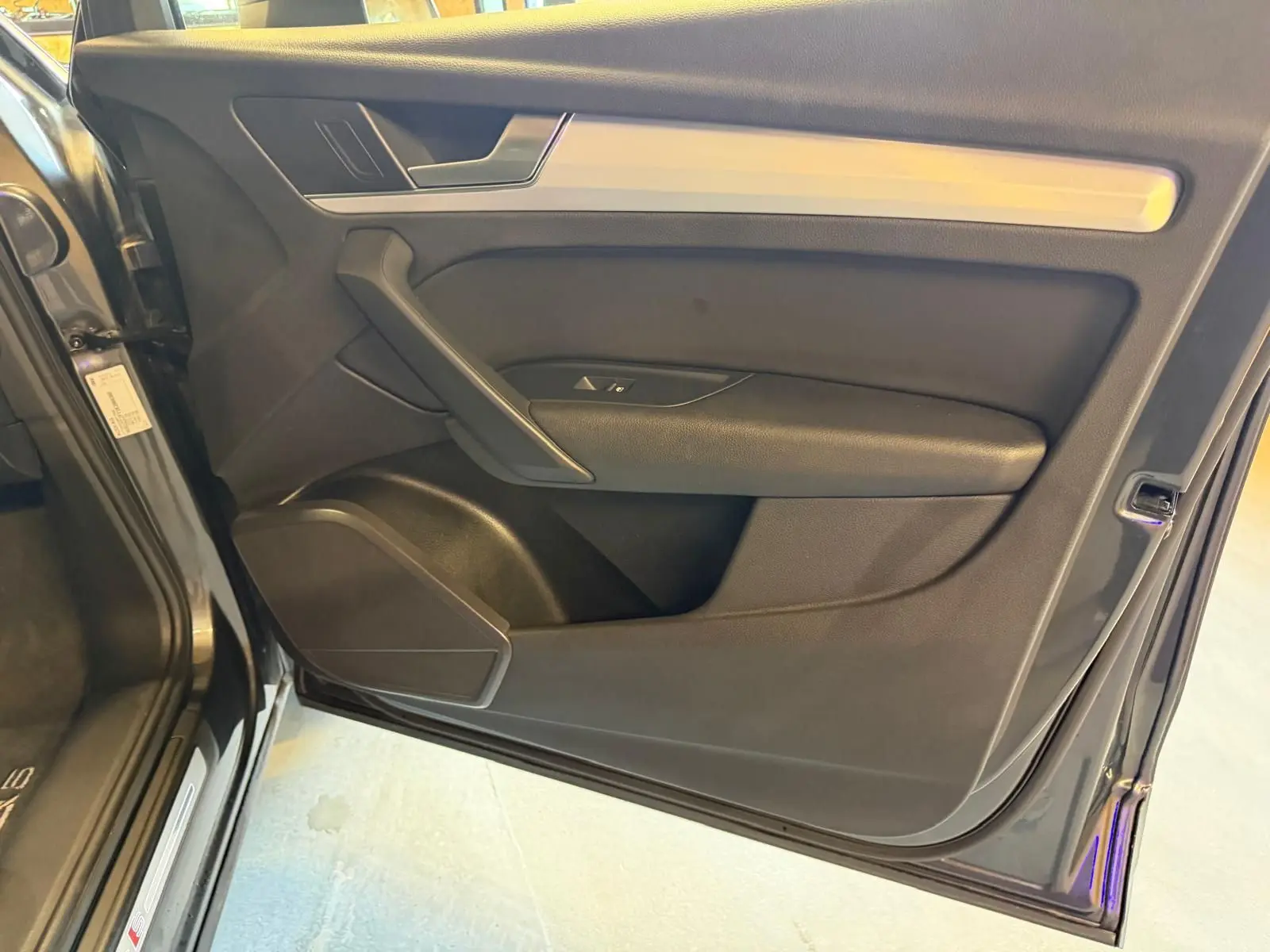 Vue intérieure de la porte avant gauche d’un Audi Q5 gris, avec garniture noire et insert aluminium.