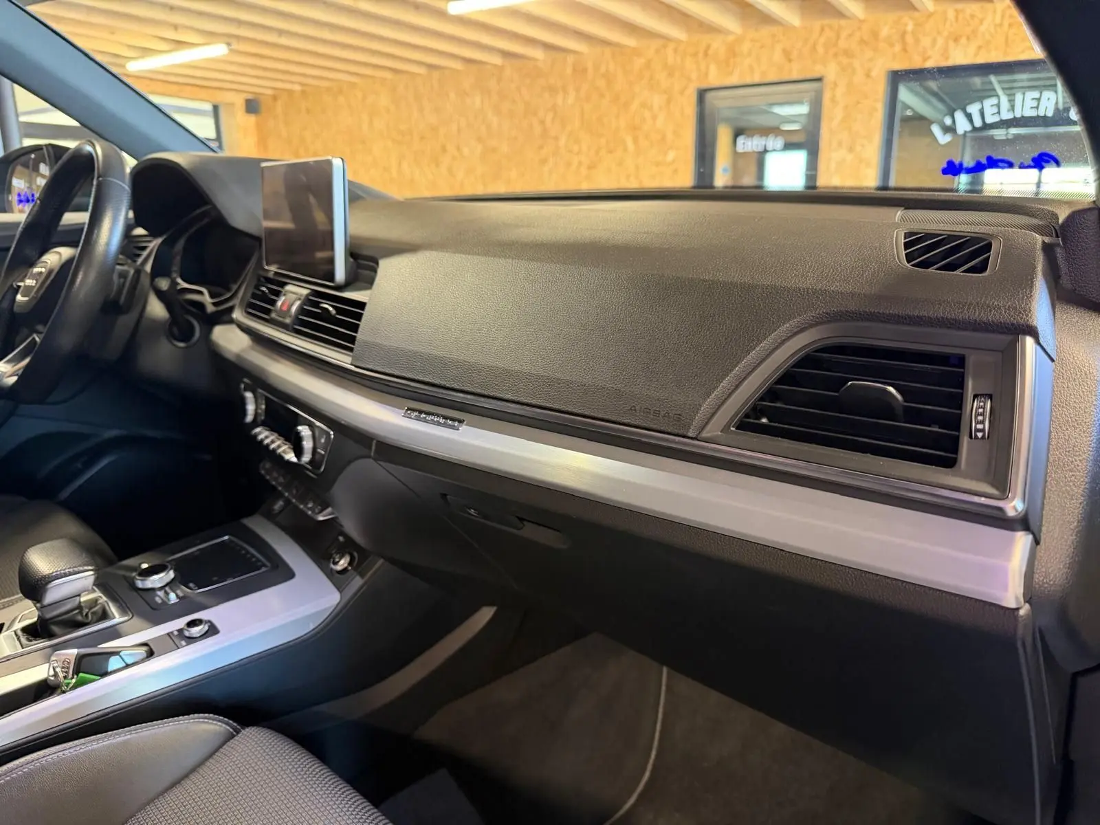 Vue intérieure côté passager du tableau de bord noir et console centrale argentée de l'Audi Q5 Sportback gris 2019.