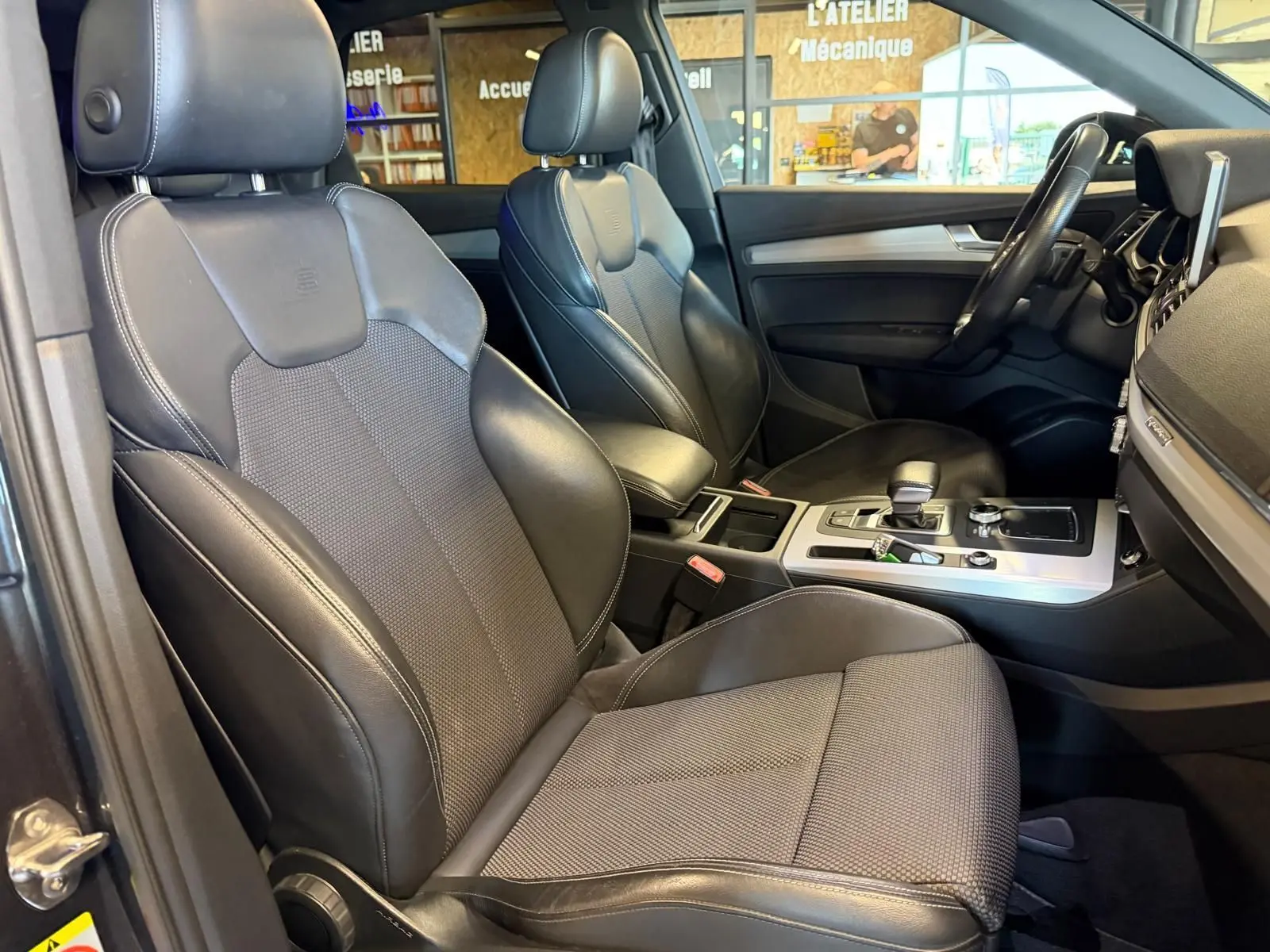 Vue intérieure côté conducteur de l'Audi Q5 Sportback 2019, sièges cuir noir avec console centrale et volant visibles.