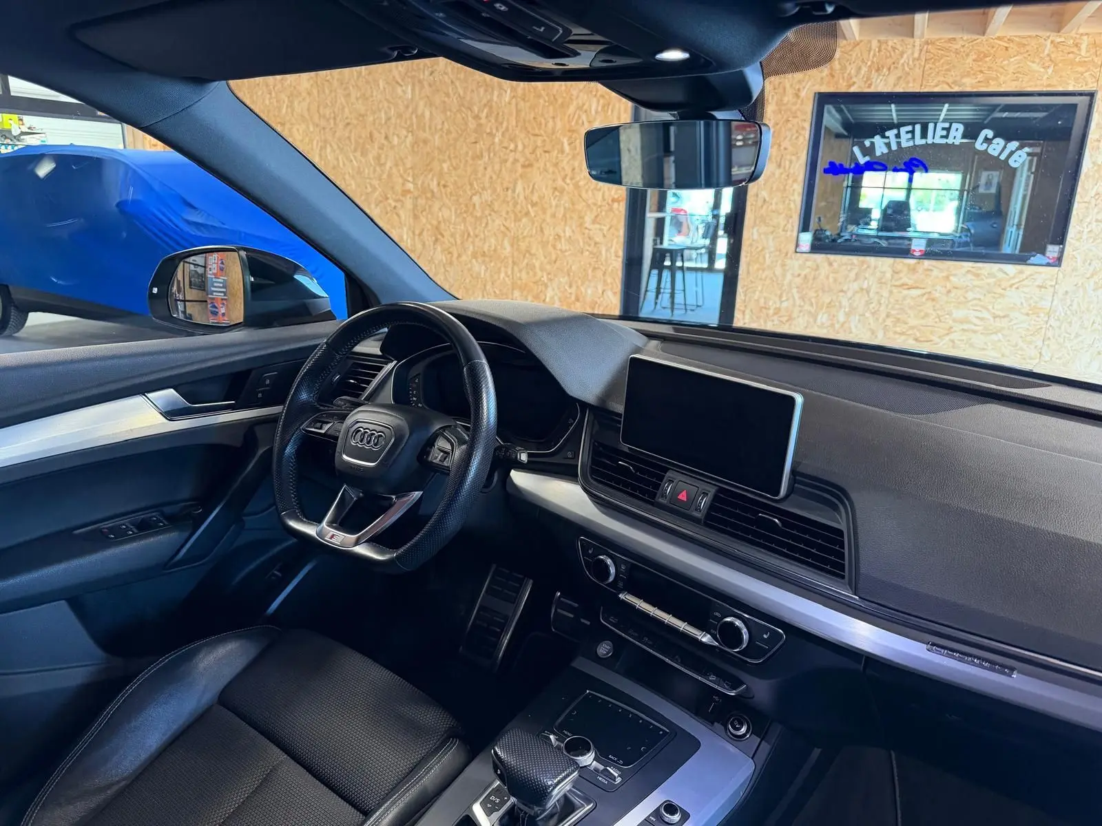 Vue intérieure côté conducteur de l'Audi Q5 Sportback gris, avec tableau de bord moderne et écran central tactile.