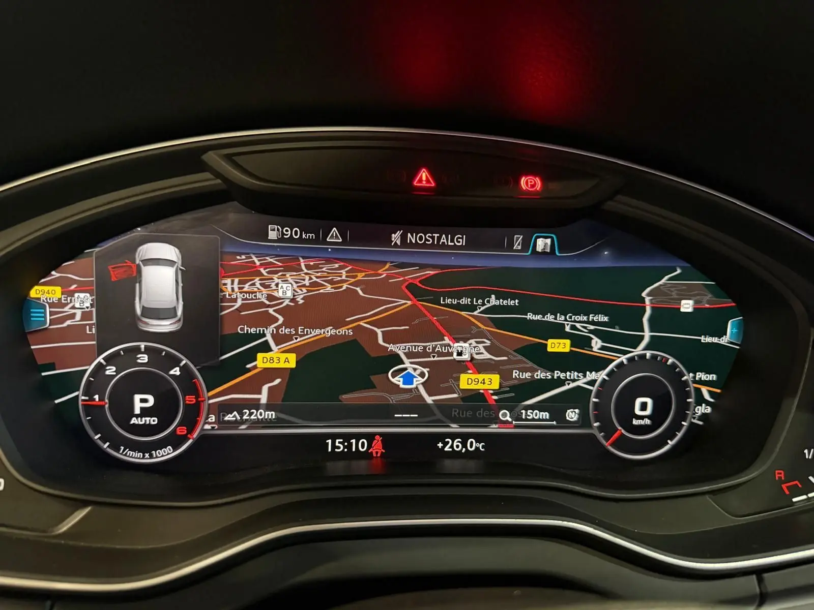 Vue rapprochée du tableau de bord numérique de l'Audi Q5 gris, affichant la navigation et les indicateurs de vitesse et régime.