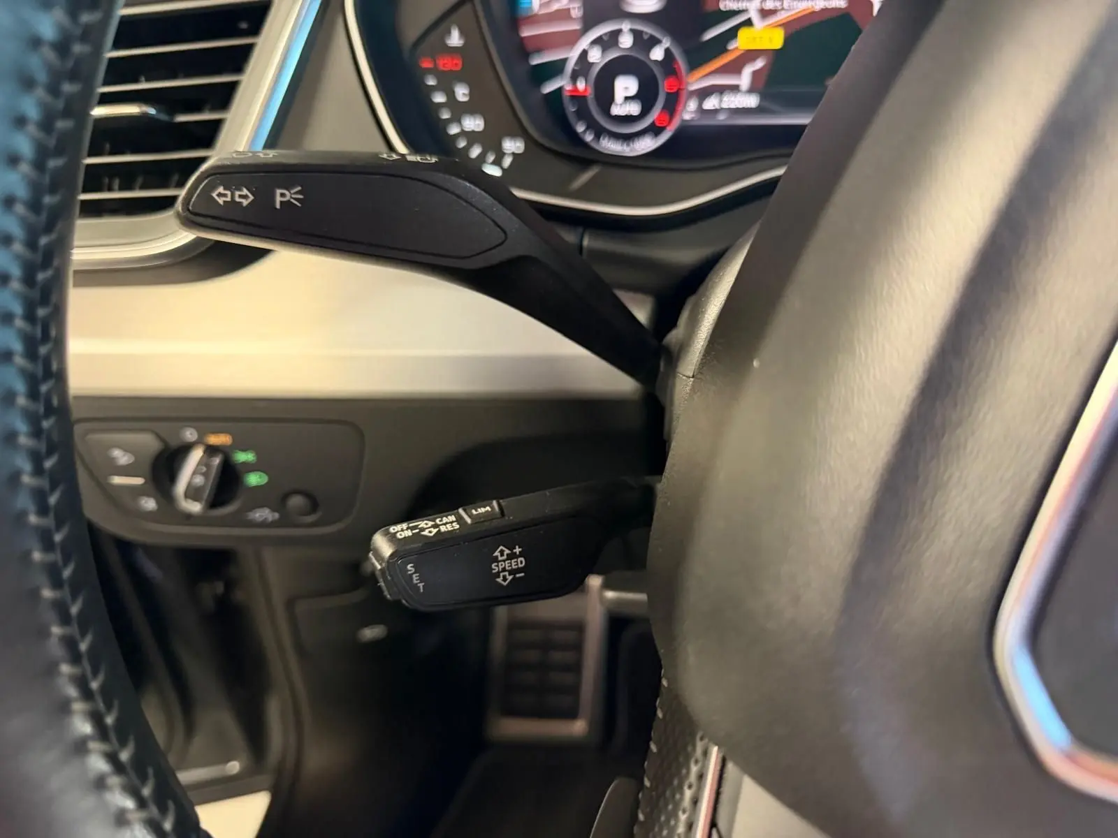 Gros plan sur la commande de régulateur de vitesse et clignotants côté gauche du volant d’un Audi Q5 Sportback gris 2019.