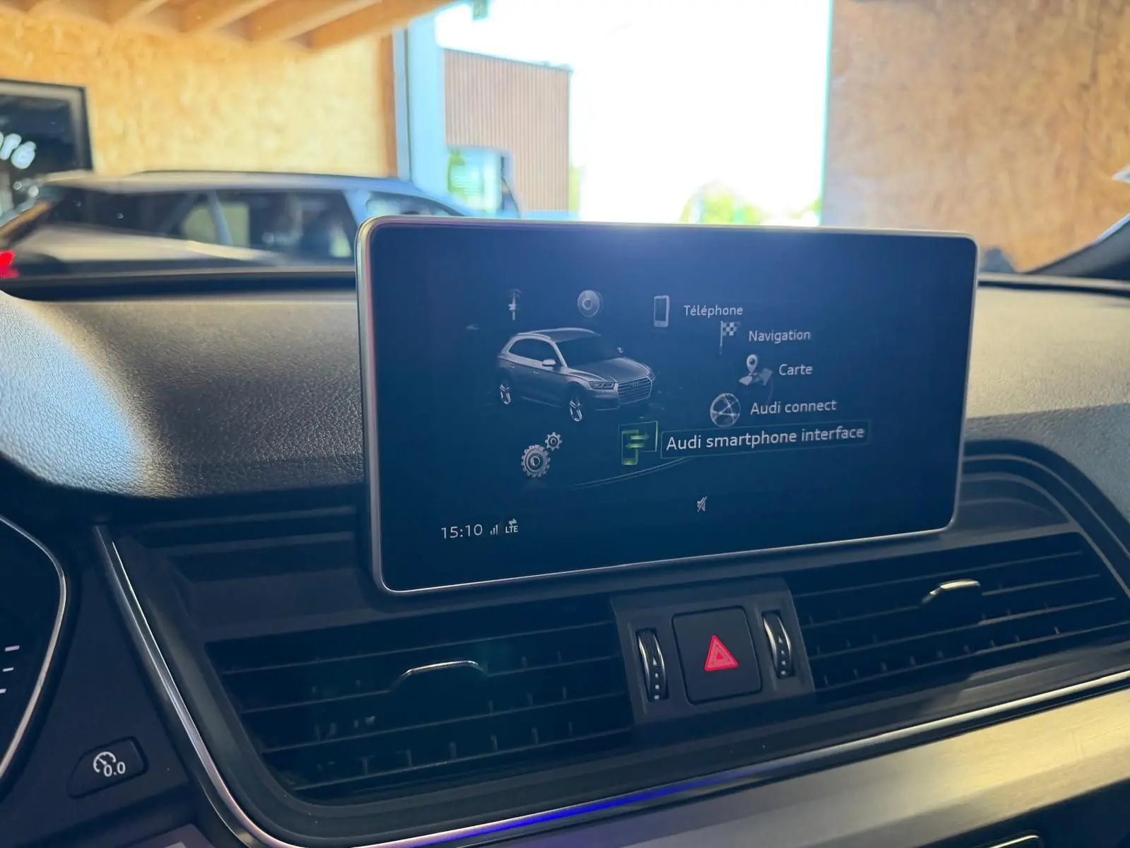Vue intérieure du tableau de bord de l'Audi Q5 Sportback gris, avec écran central affichant l'interface smartphone.
