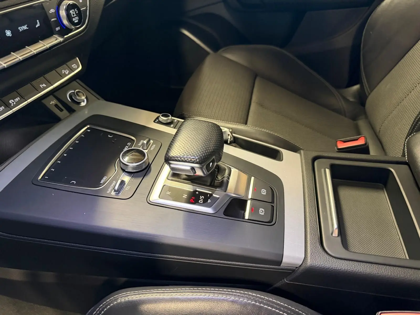 Vue rapprochée de la console centrale et levier de vitesse du Audi Q5 Sportback gris, intérieur noir avec commandes modernes.