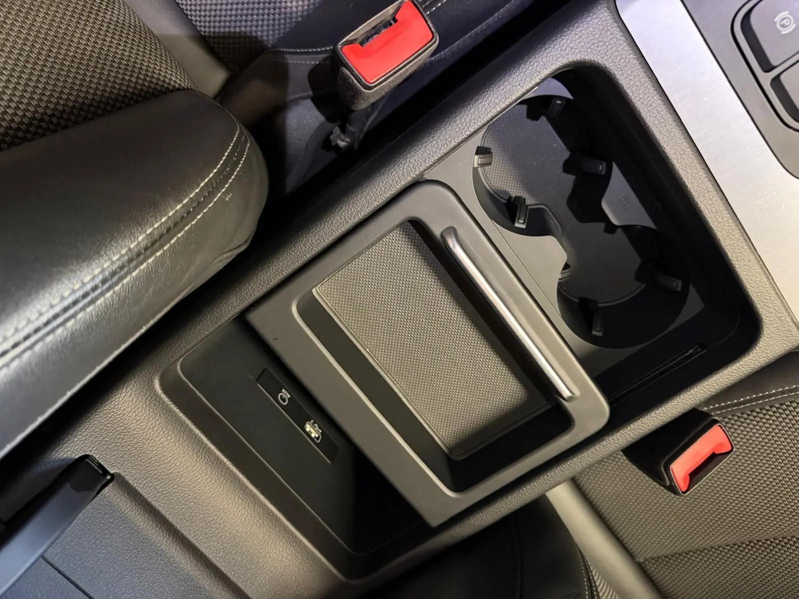 Gros plan sur la console centrale noire de l’Audi Q5 Sportback 2019, avec porte-gobelets et ports USB visibles.