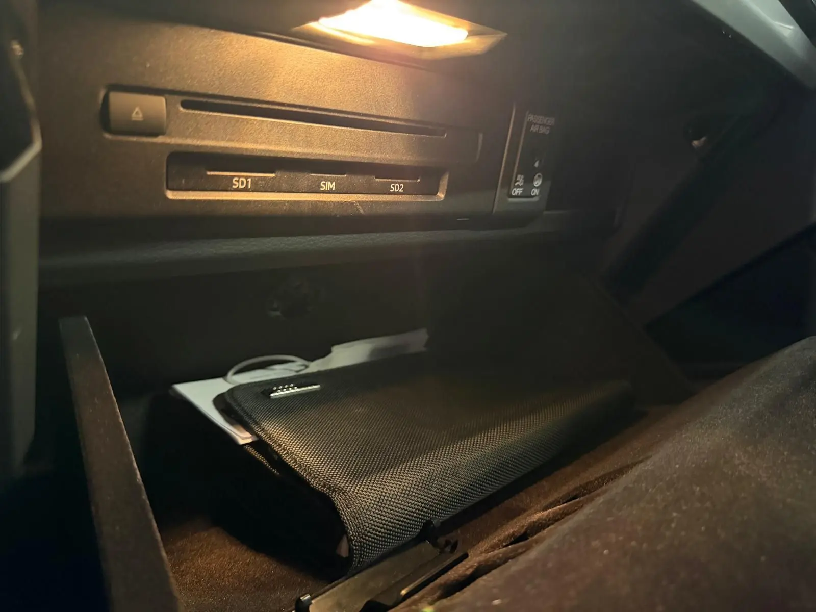Gros plan sur la boîte à gants ouverte de l'Audi Q5 Sportback 2019 avec pochette noire et éclairage intérieur.