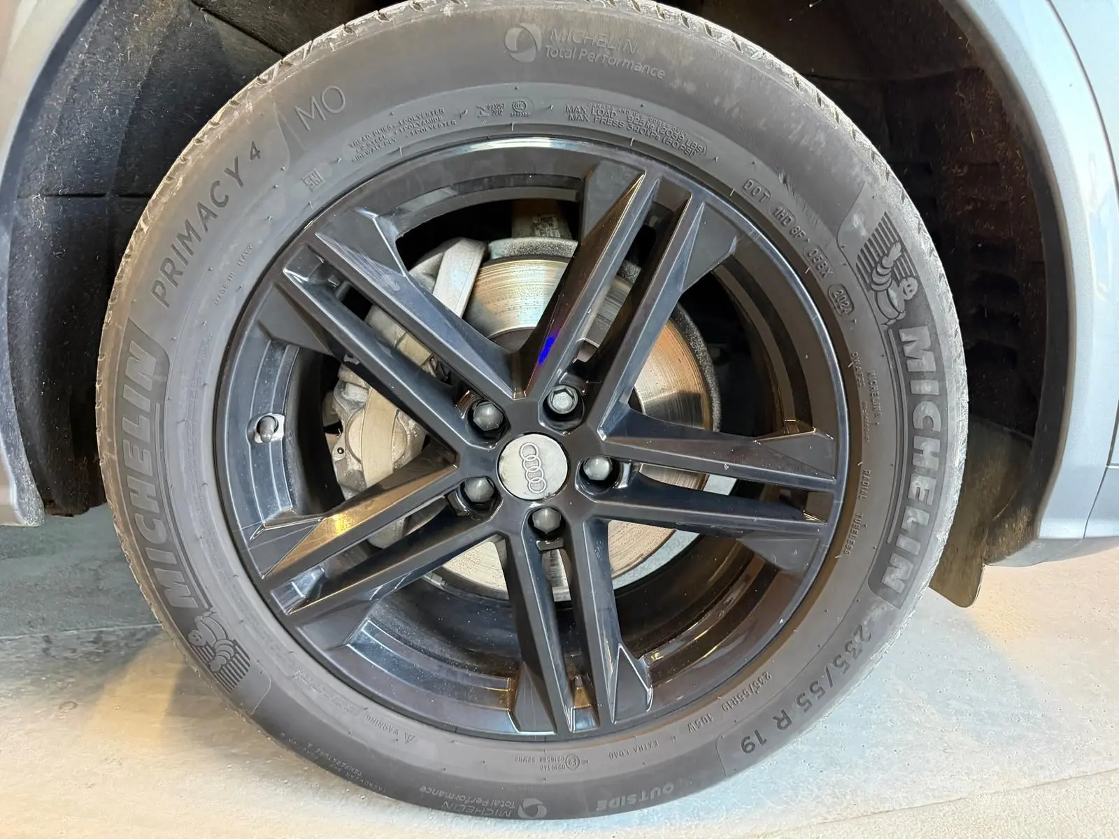 Gros plan sur la roue avant droite d’un Audi Q5 Sportback gris, jante alliage noir à 5 doubles branches.