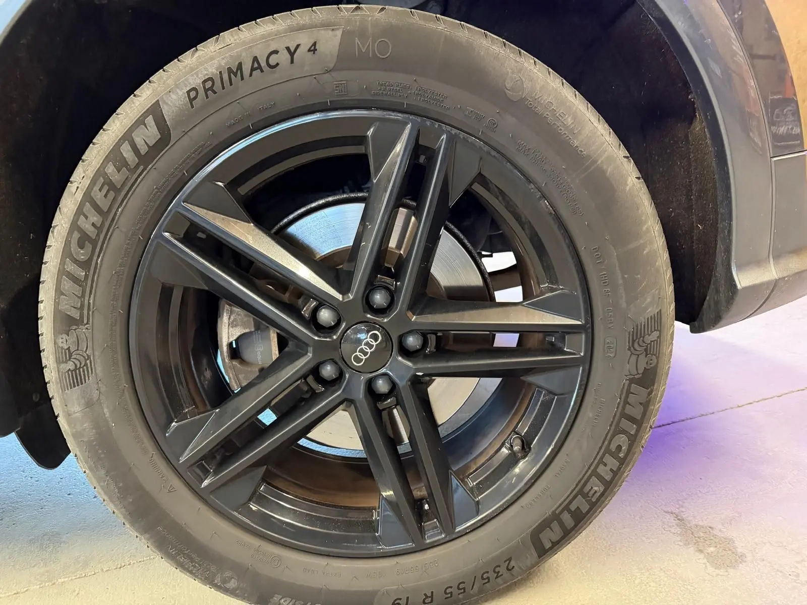 Gros plan sur la roue avant droite avec jante noire et pneu Michelin d’un Audi Q5 Sportback gris.