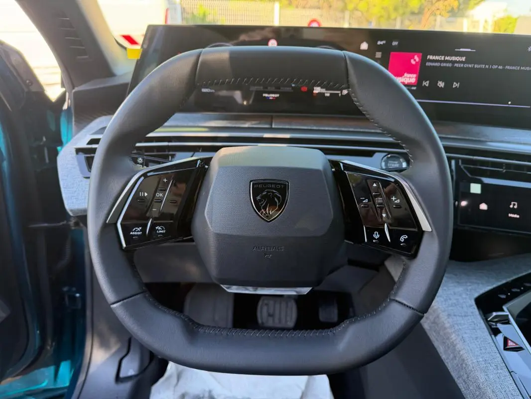Vue rapprochée du volant cuir noir du Peugeot 3008 Hybrid 145 e-DCS6 Allure bleu 2025, avec commandes intégrées.