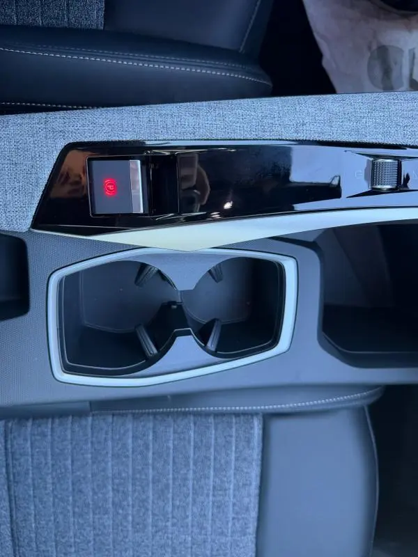 Gros plan sur la console centrale du Peugeot 3008 Hybrid 145 e-DCS6 Allure 2025, avec porte-gobelets et frein à main électrique.