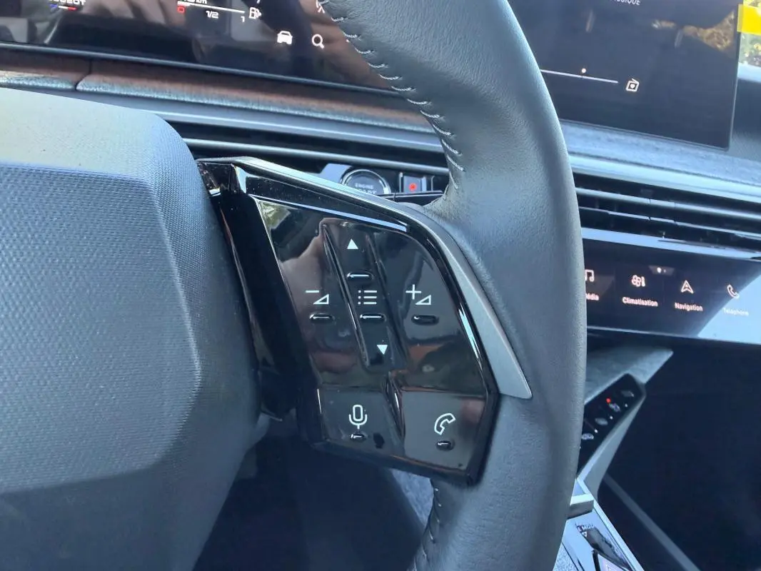 Gros plan sur les commandes au volant du Peugeot 3008 Hybrid 145 e-DCS6 Allure 2025, intérieur noir avec écran tactile.