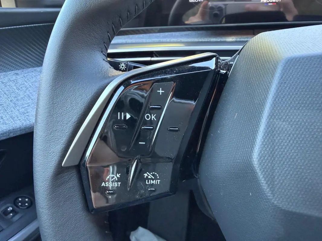 Gros plan sur les commandes au volant côté gauche du Peugeot 3008 Hybrid bleu, avec boutons de régulateur et volume.