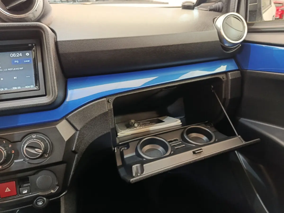 Intérieur de l'AIXAM AMBITION 0.5 CITY COUPE GTI 2023, vue sur la boîte à gants ouverte avec bandeau bleu et console centrale.
