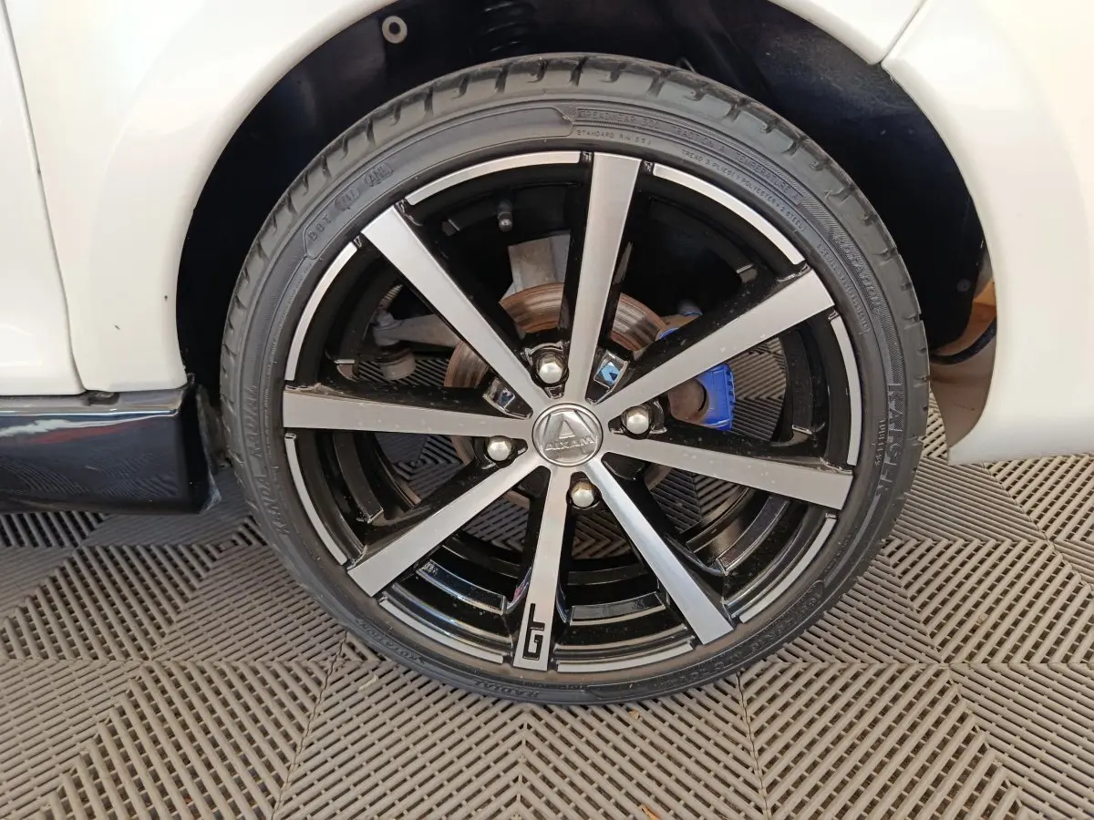 Gros plan sur la roue avant droite de l'AIXAM AMBITION 0.5 CITY COUPE GTI blanche avec jante noire et argentée, détail GTI visible.