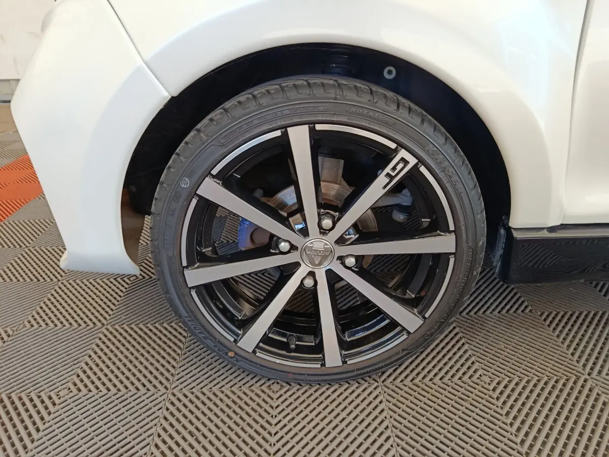 Gros plan sur la roue avant gauche de l'AIXAM AMBITION 0.5 CITY COUPE GTI blanche avec jante noire et argentée.