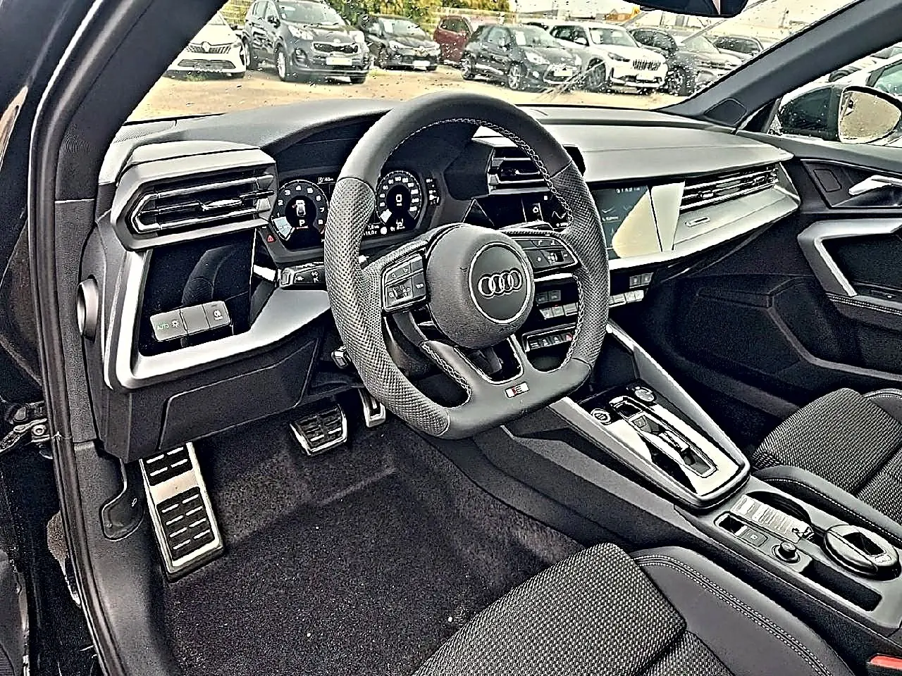 Vue intérieure côté conducteur de l'Audi A3 Sportback 2026, volant sport cuir et tableau de bord digital noir.