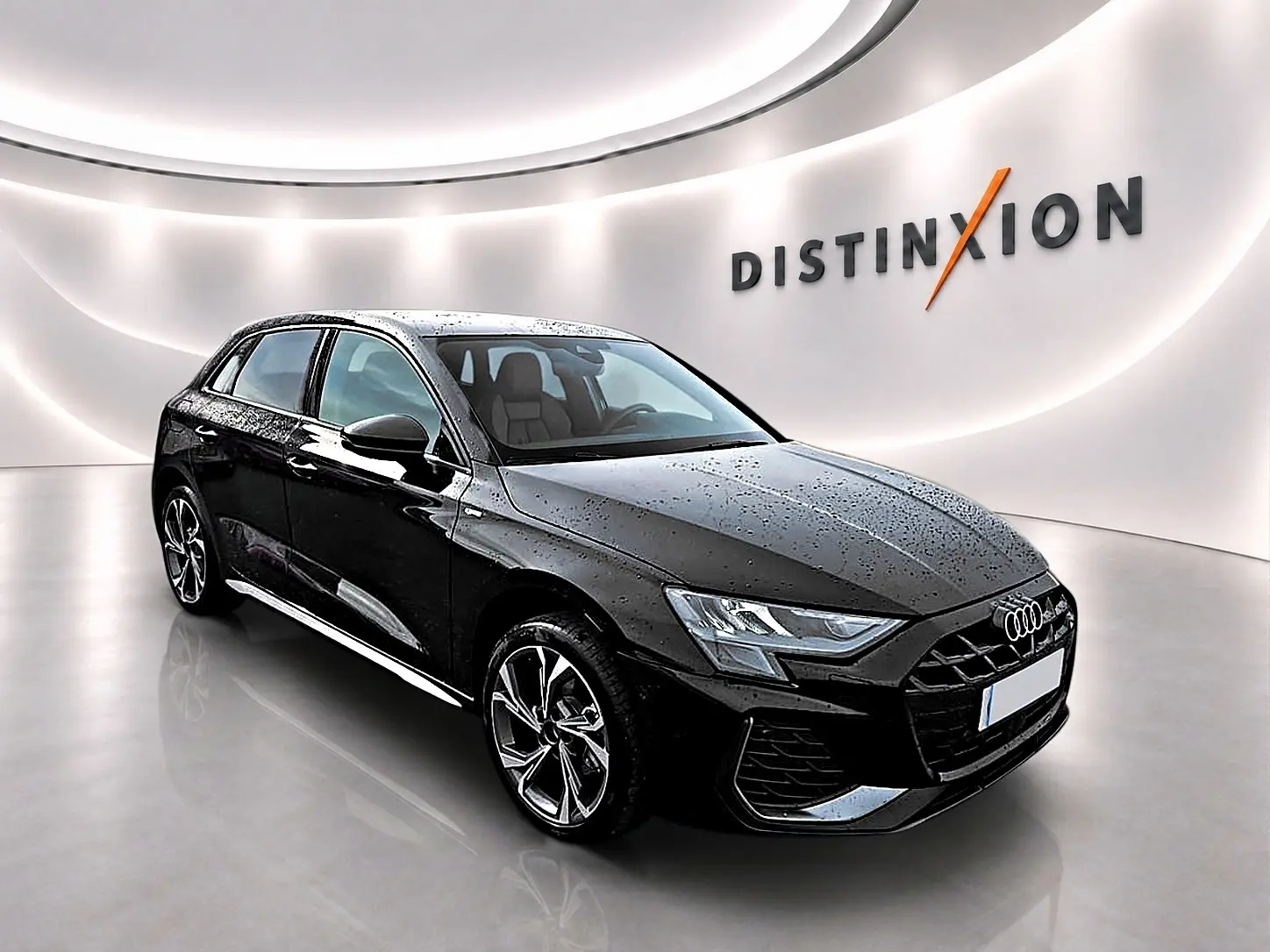 Audi A3 Sportback noir Mythos en 3/4 avant droit avec jantes alu et éclairage LED, dans un showroom lumineux.