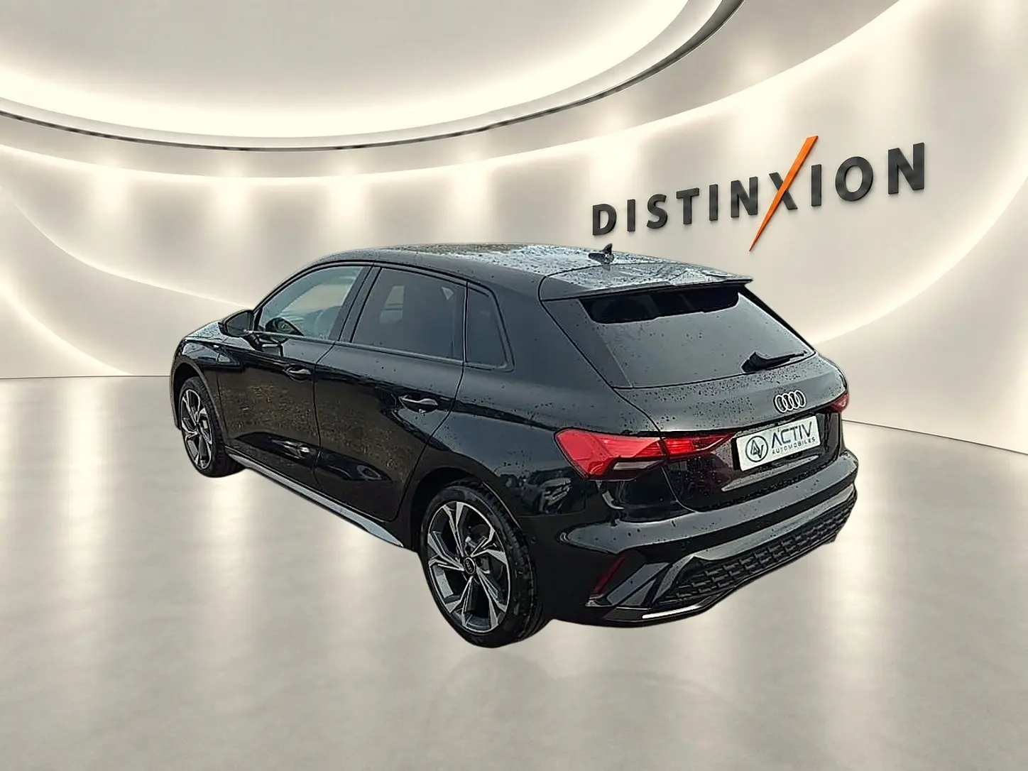 Audi A3 Sportback noir Mythos vue 3/4 arrière droit dans un showroom lumineux avec jantes alu distinctives.