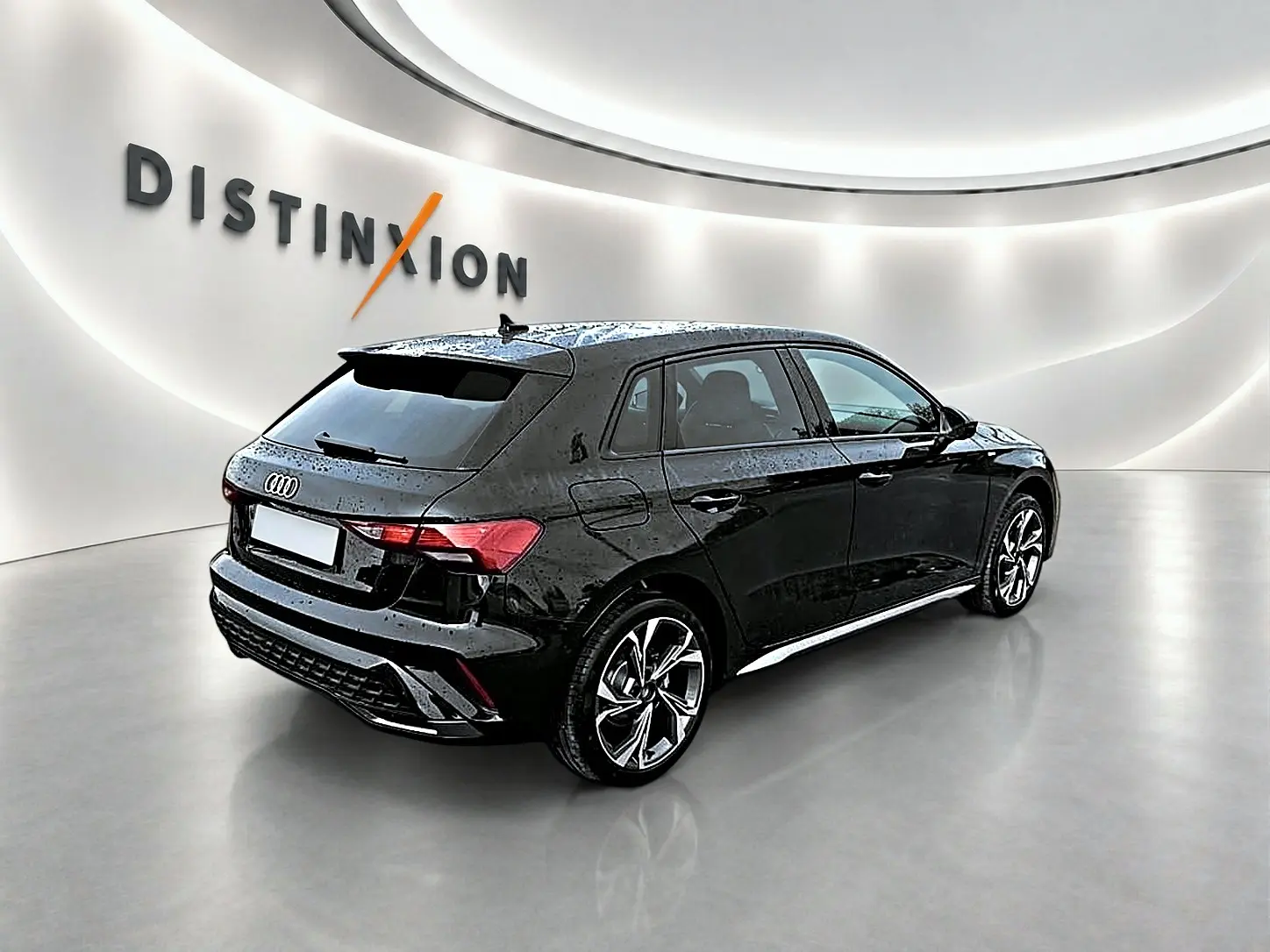 Audi A3 Sportback noir Mythos vue 3/4 arrière droit dans un showroom lumineux avec jantes alu graphiques.