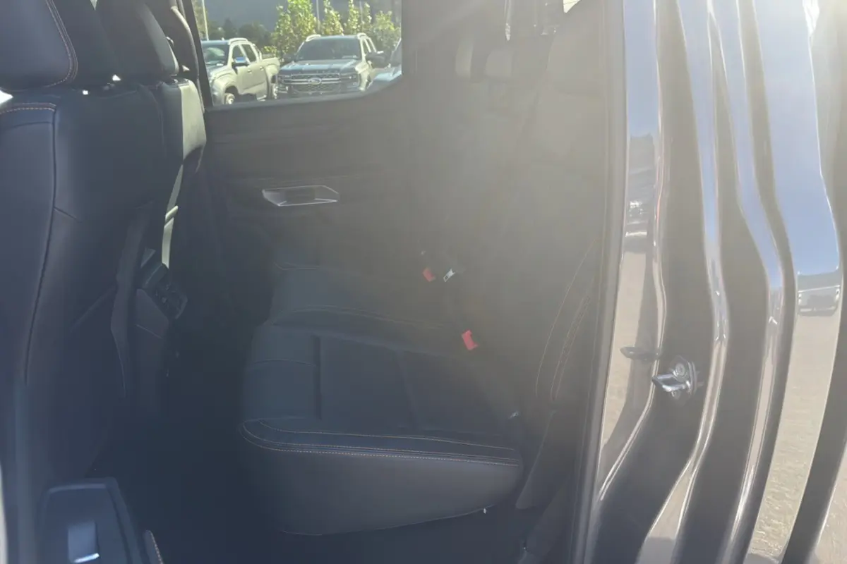 Vue intérieure côté arrière droit du Ford Ranger 2026 gris carbone, montrant les sièges arrière en cuir avec surpiqûres contrastantes.