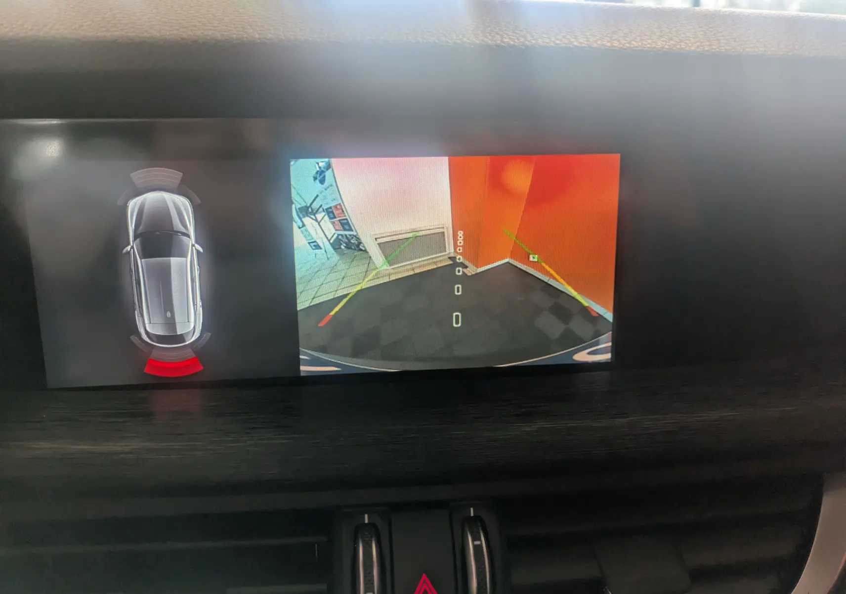 Écran multimédia d'Alfa Romeo Stelvio blanc montrant la caméra de recul avec détection d'obstacle arrière en intérieur.