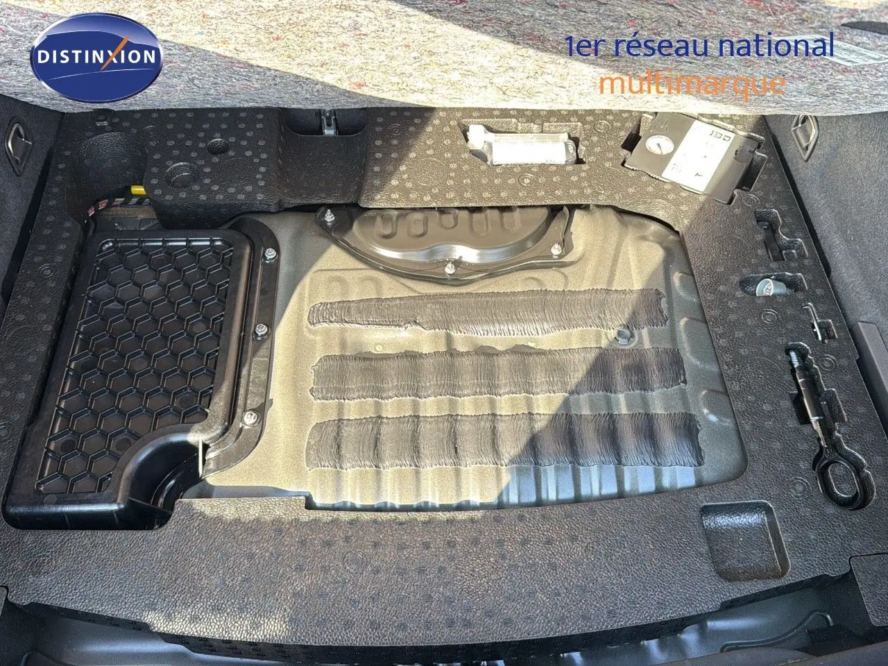 Vue plongeante sur le coffre ouvert d'une CUPRA Formentor noir minuit, montrant le rangement sous plancher et outils intégrés.