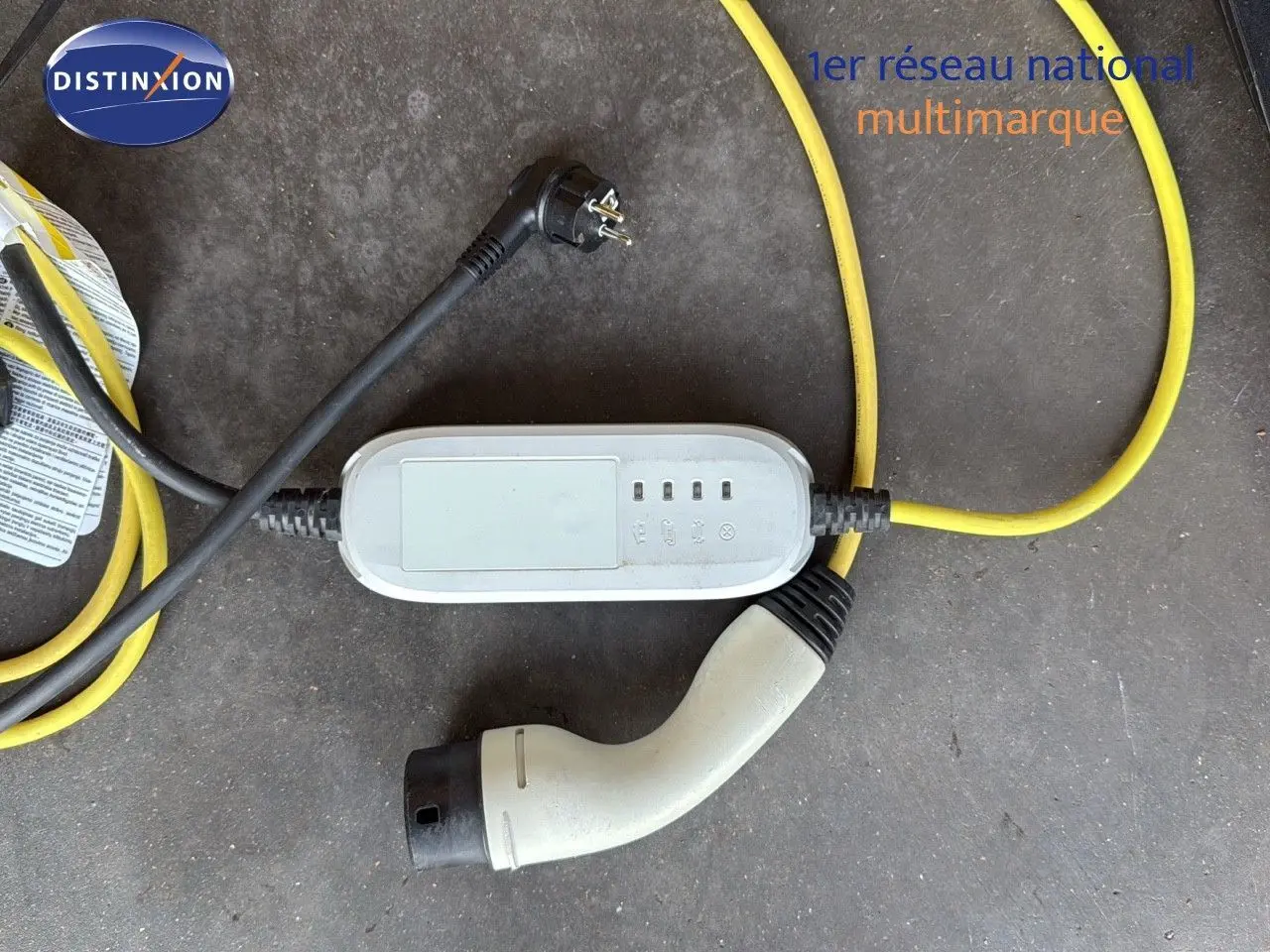 Câble de recharge hybride avec prise blanche et câble jaune sur sol gris, accessoire du CUPRA Formentor noir minuit.