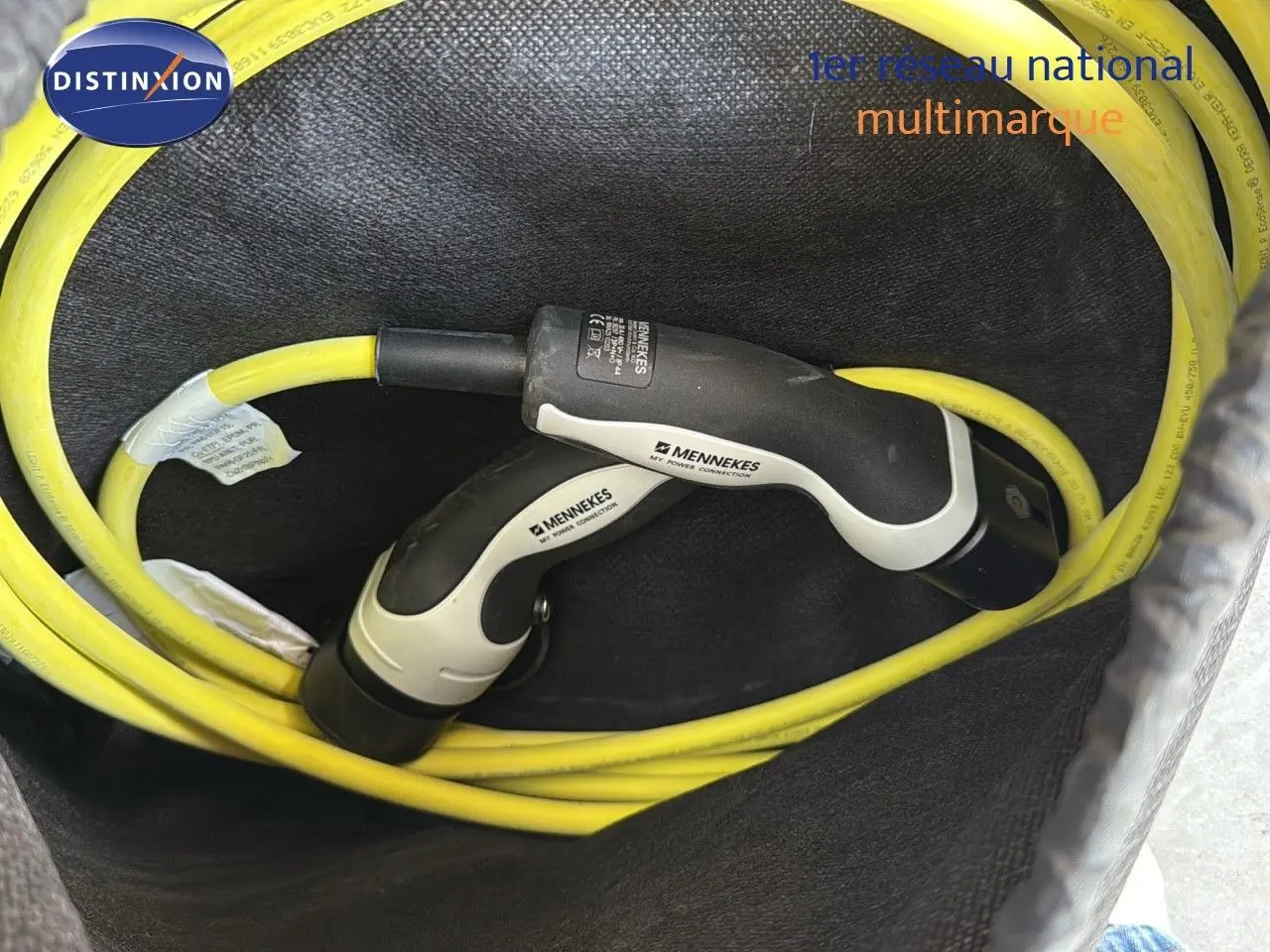 Câble de recharge jaune Mennekes enroulé dans le coffre d'un CUPRA Formentor noir minuit hybride rechargeable.