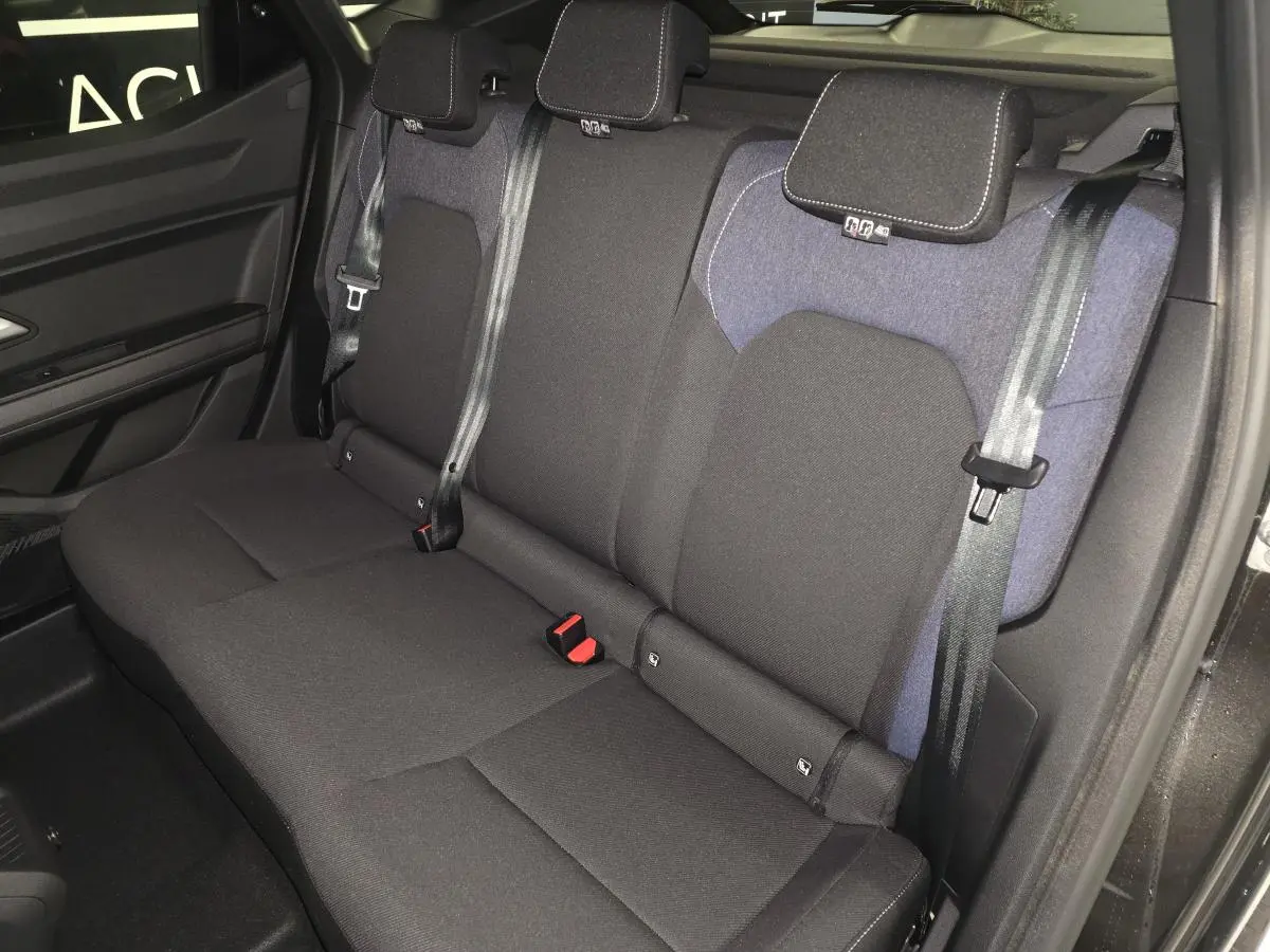 Vue intérieure de la banquette arrière du Dacia Duster 1.6 Hybrid 2025 avec sellerie Denim bleu et ceintures noires.