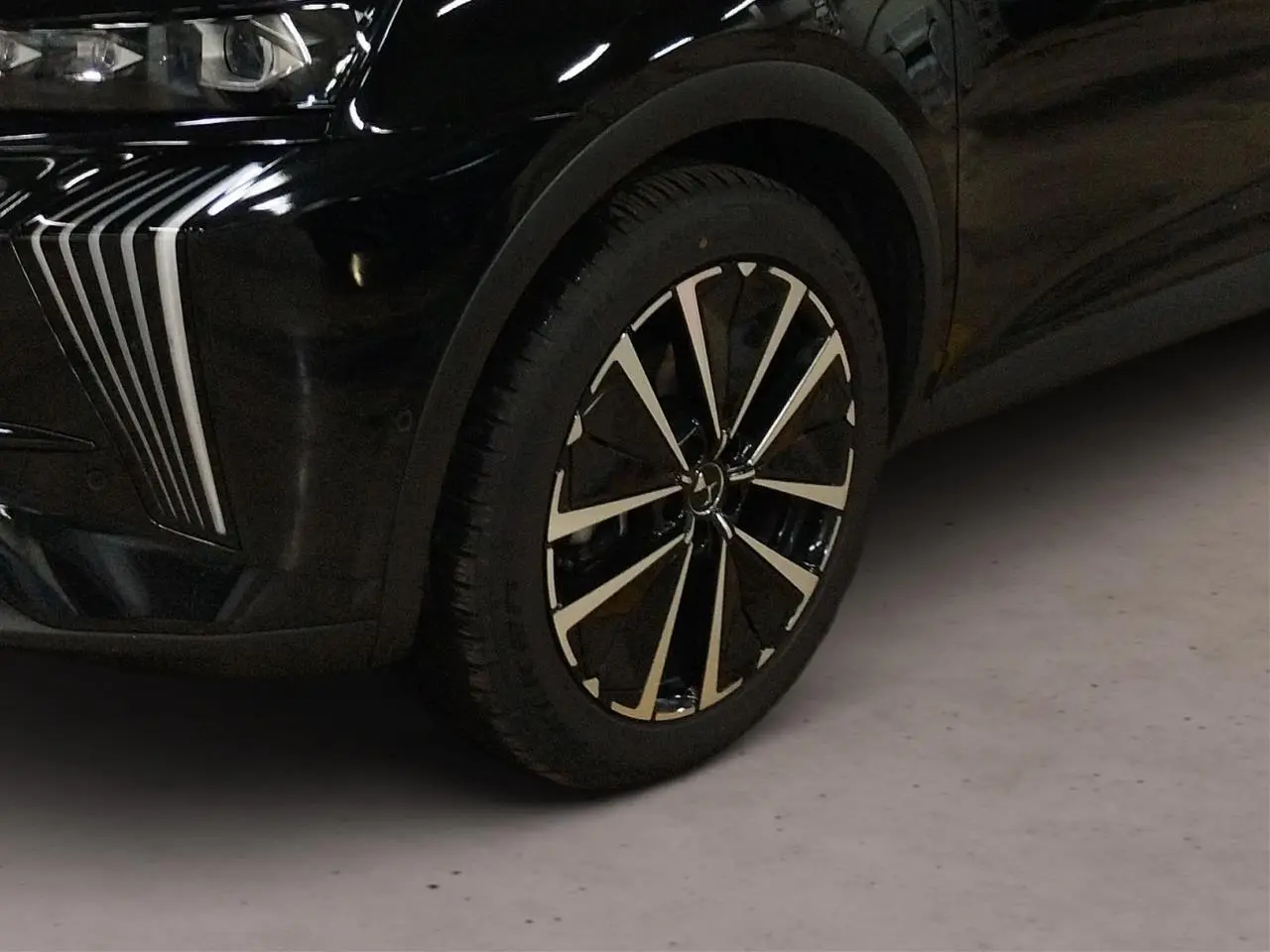 Gros plan sur la roue avant droite et le pare-chocs avant noir Perla du DS7 avec détails chromés verticaux.